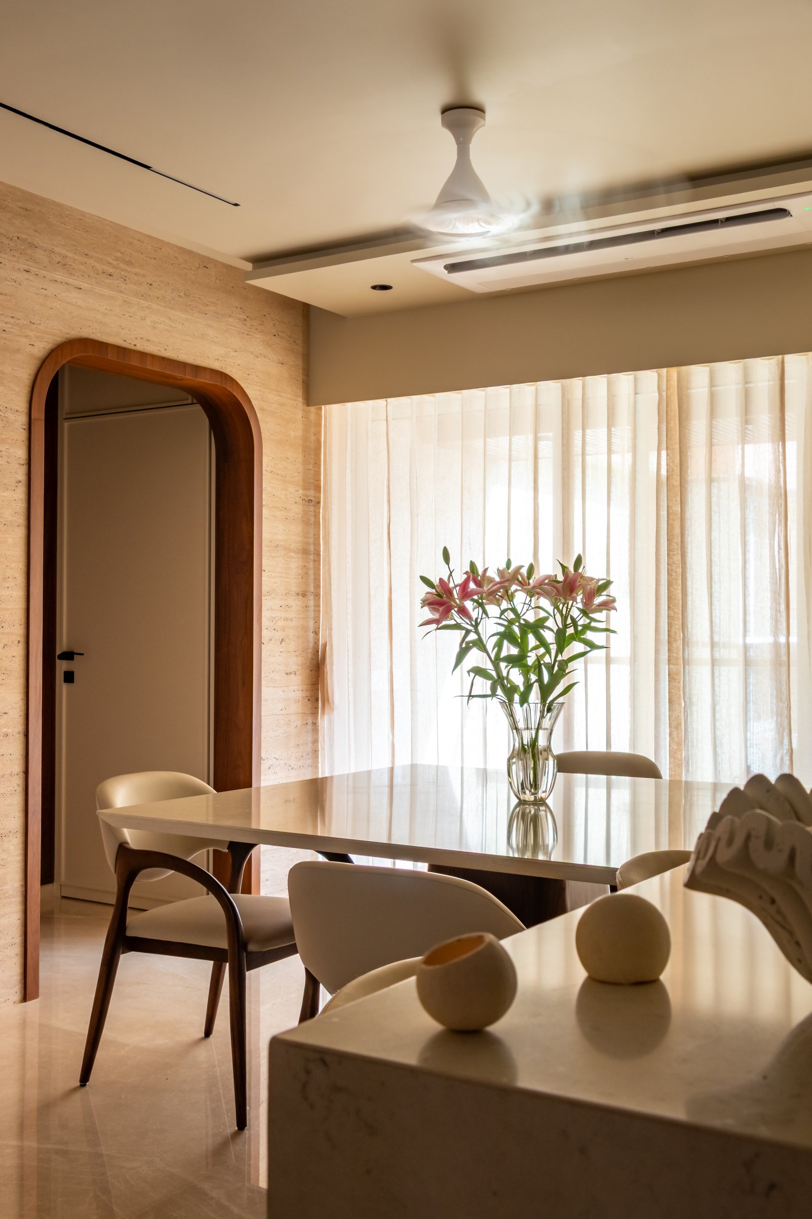 A walnut-framed arched doorway marks the passage from the dining area towards the bedrooms