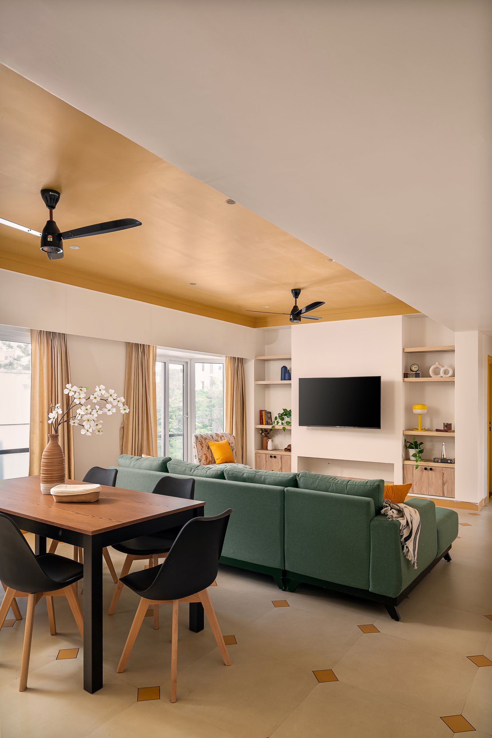 The living and dining zone, unified by an ochre tray ceiling that defines the seating area without walls