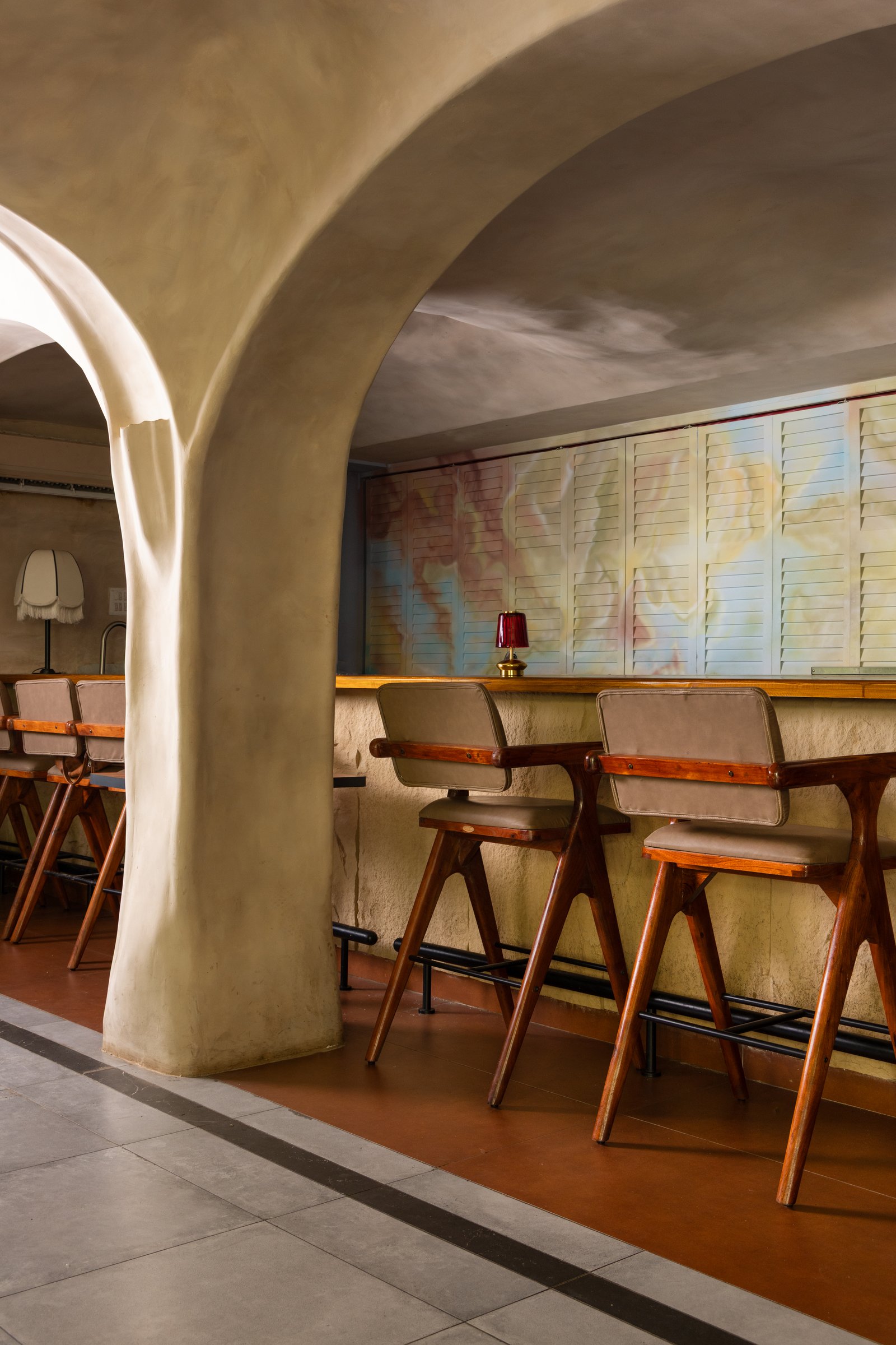 The bar counter by day, its louvred shutters closed and painted as a soft cloudscape mural