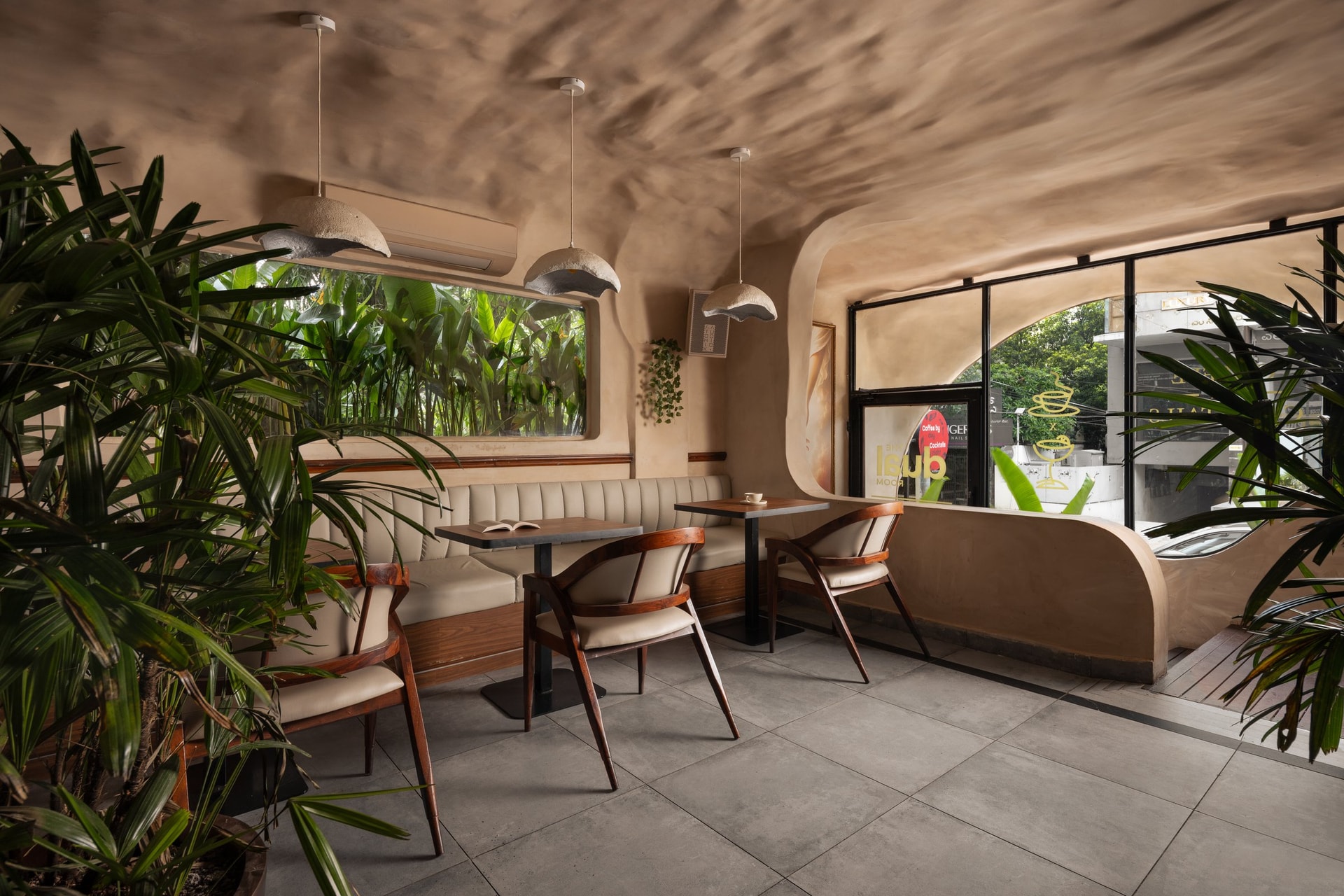 The daytime café, where sculpted plaster and hand-formed pendants frame a view into the planted street edge