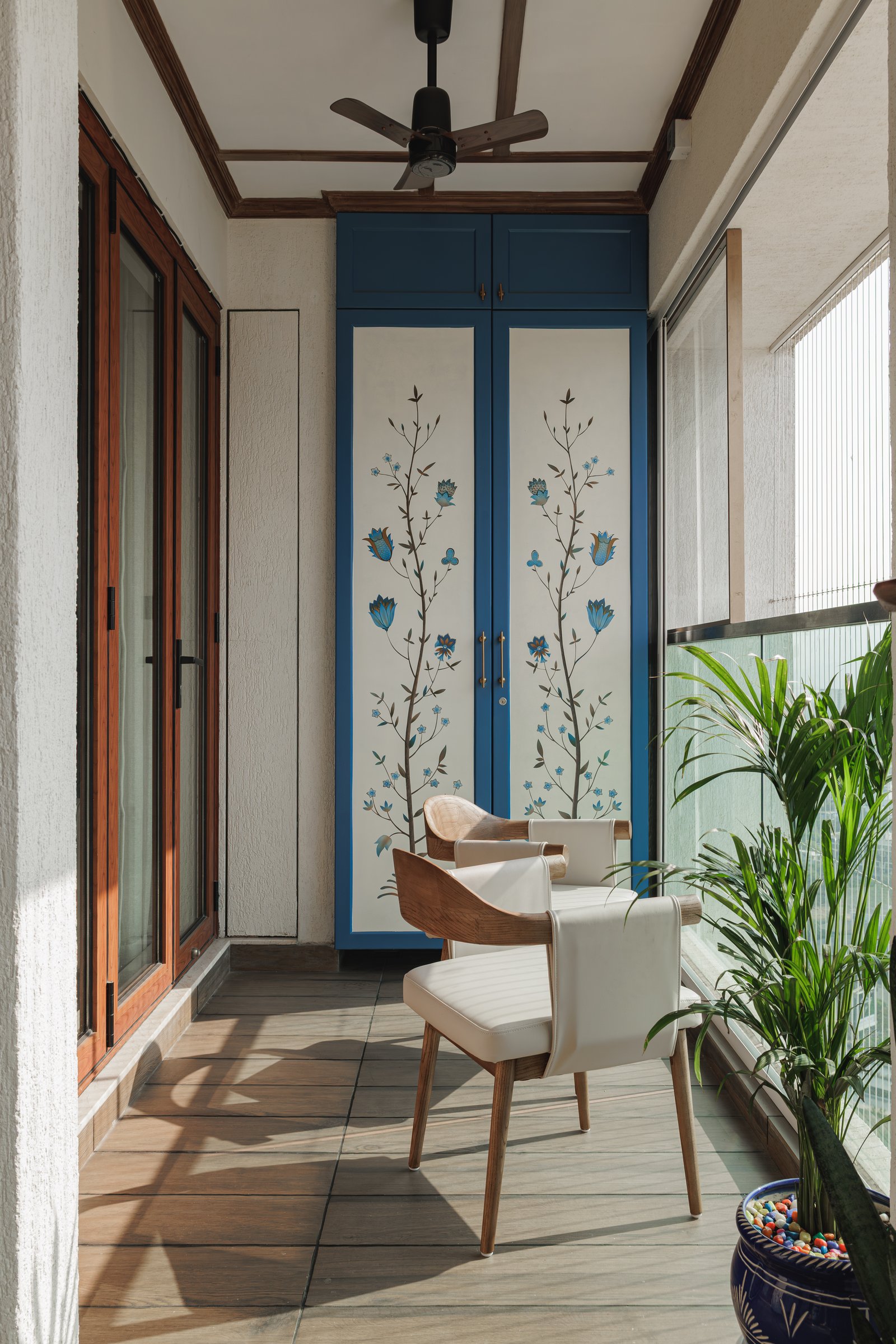 The balcony, where a hand-painted blue cabinet and a pair of curved timber chairs form an informal retreat