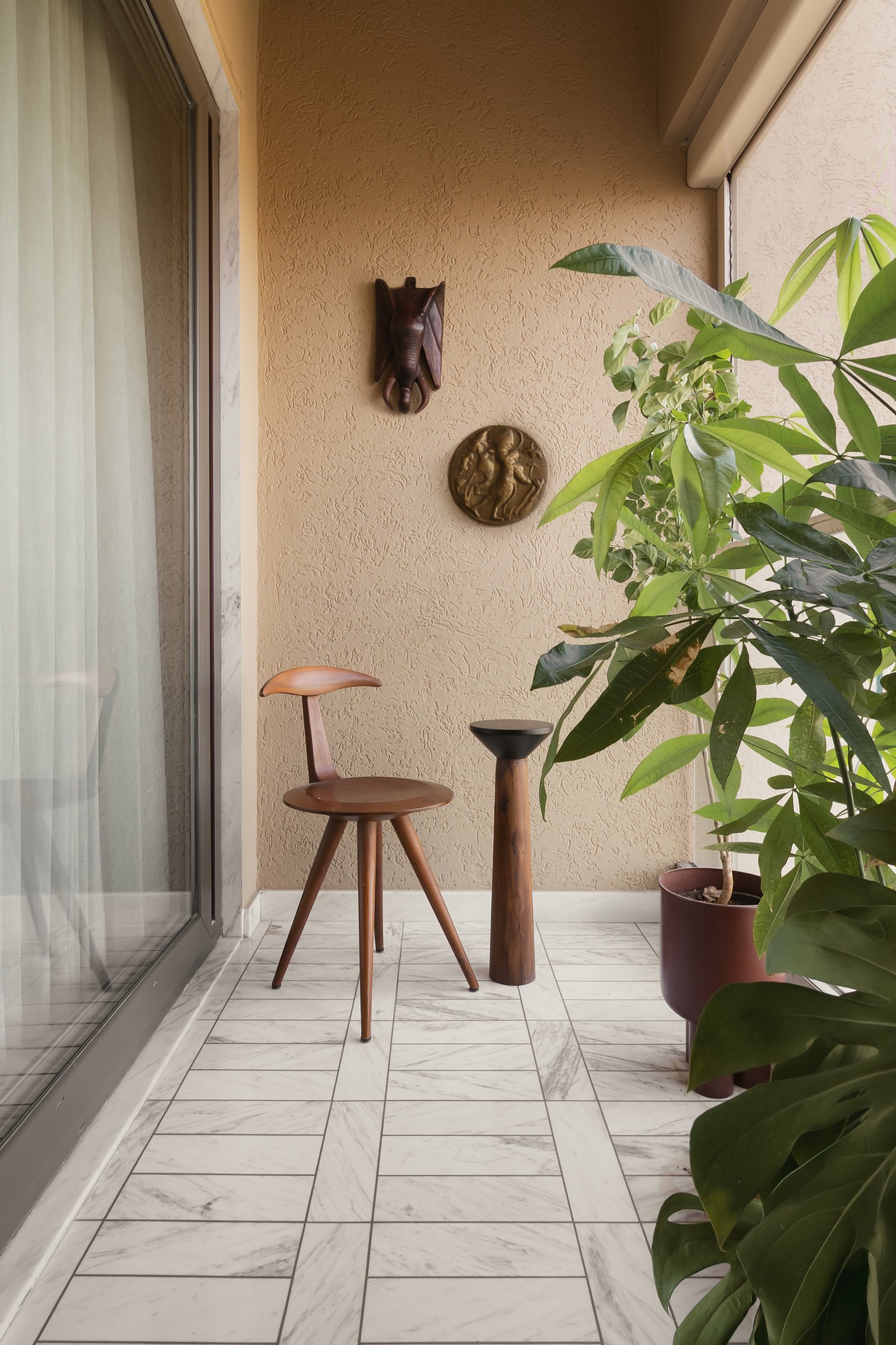 The balcony, where textured plaster and marble paving frame a still life of collected objects against dense foliage