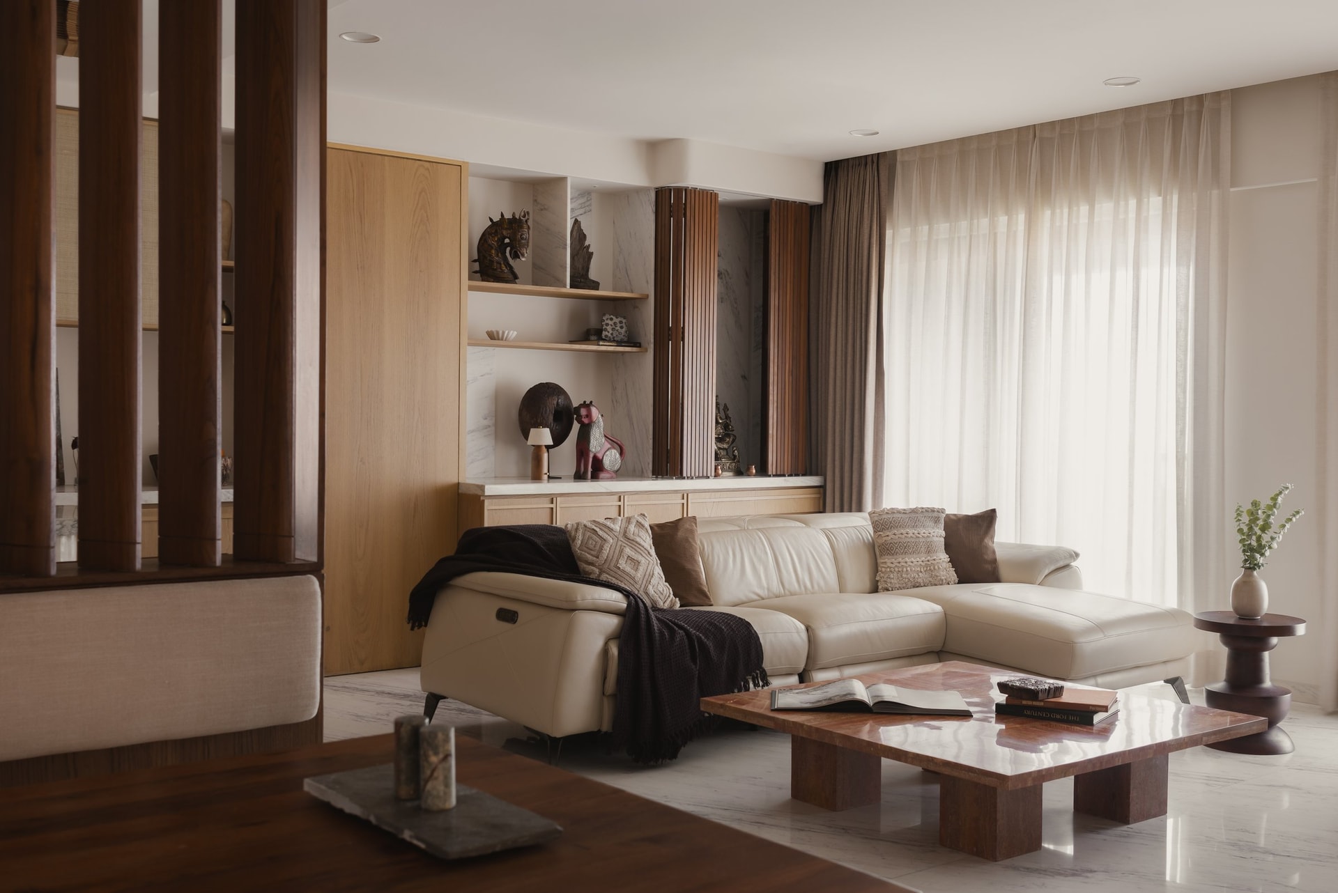 The living room, anchored by a bespoke red travertine coffee table set against an ivory leather sectional