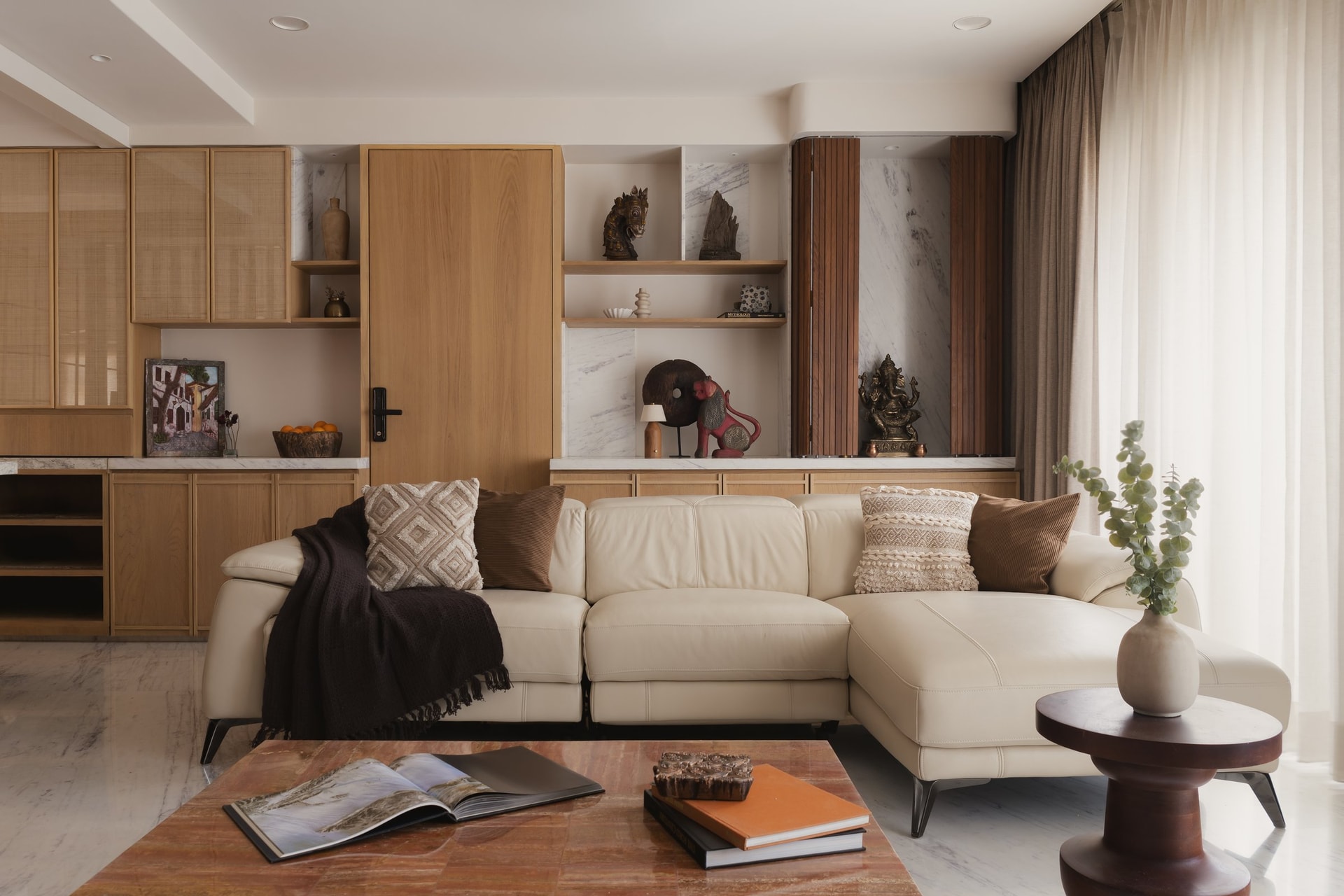 Open shelving against Banswara marble backing holds collected objects, with a slatted teak screen concealing the puja niche