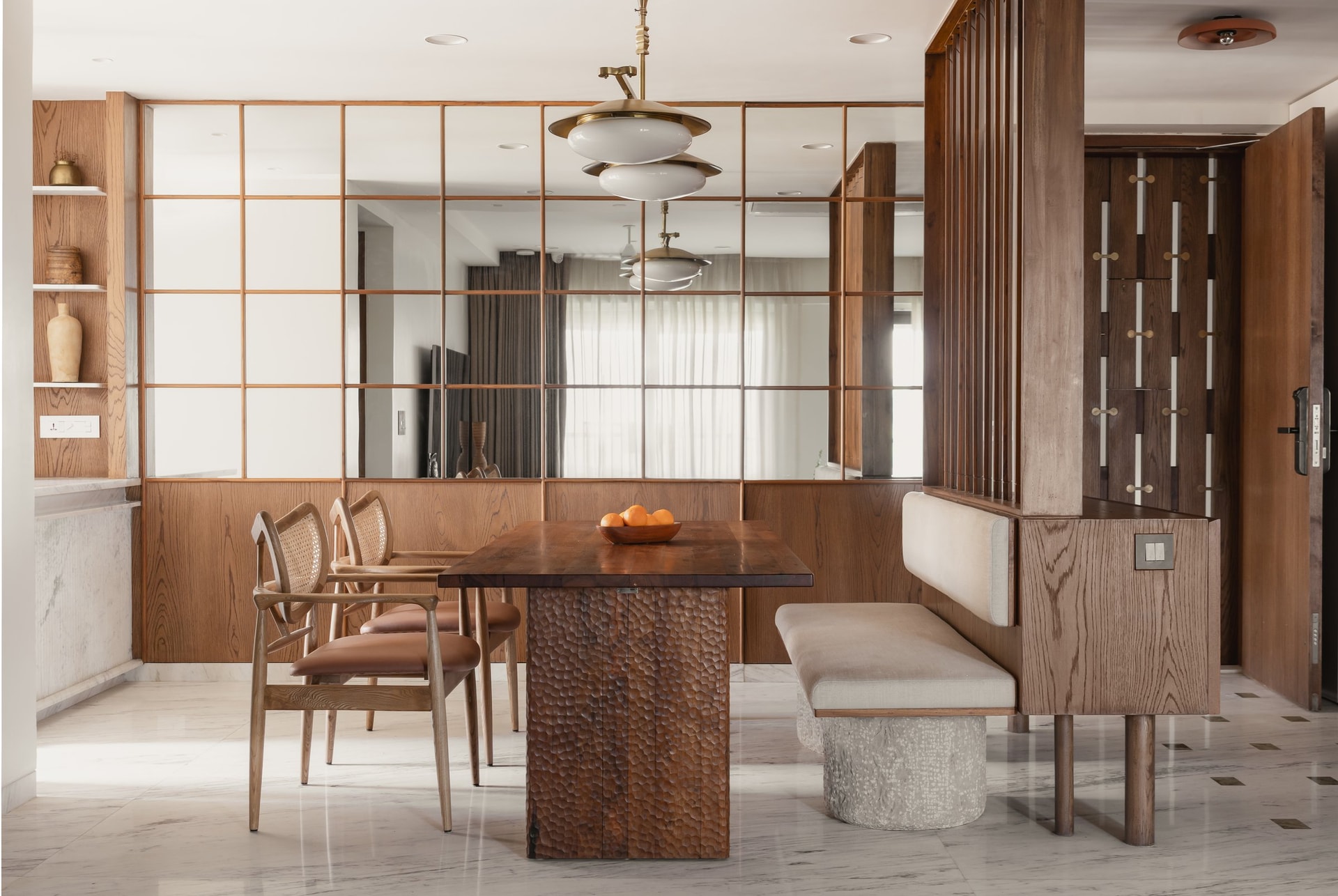 The dining area, framed by a grid-framed mirrored wall that multiplies natural light from the living room