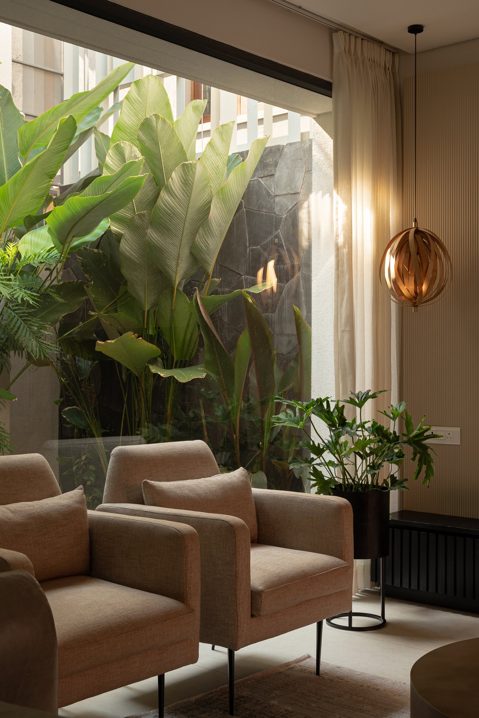 A closer view of the seating by the courtyard glazing, where planting and stone read as a fifth surface of the room
