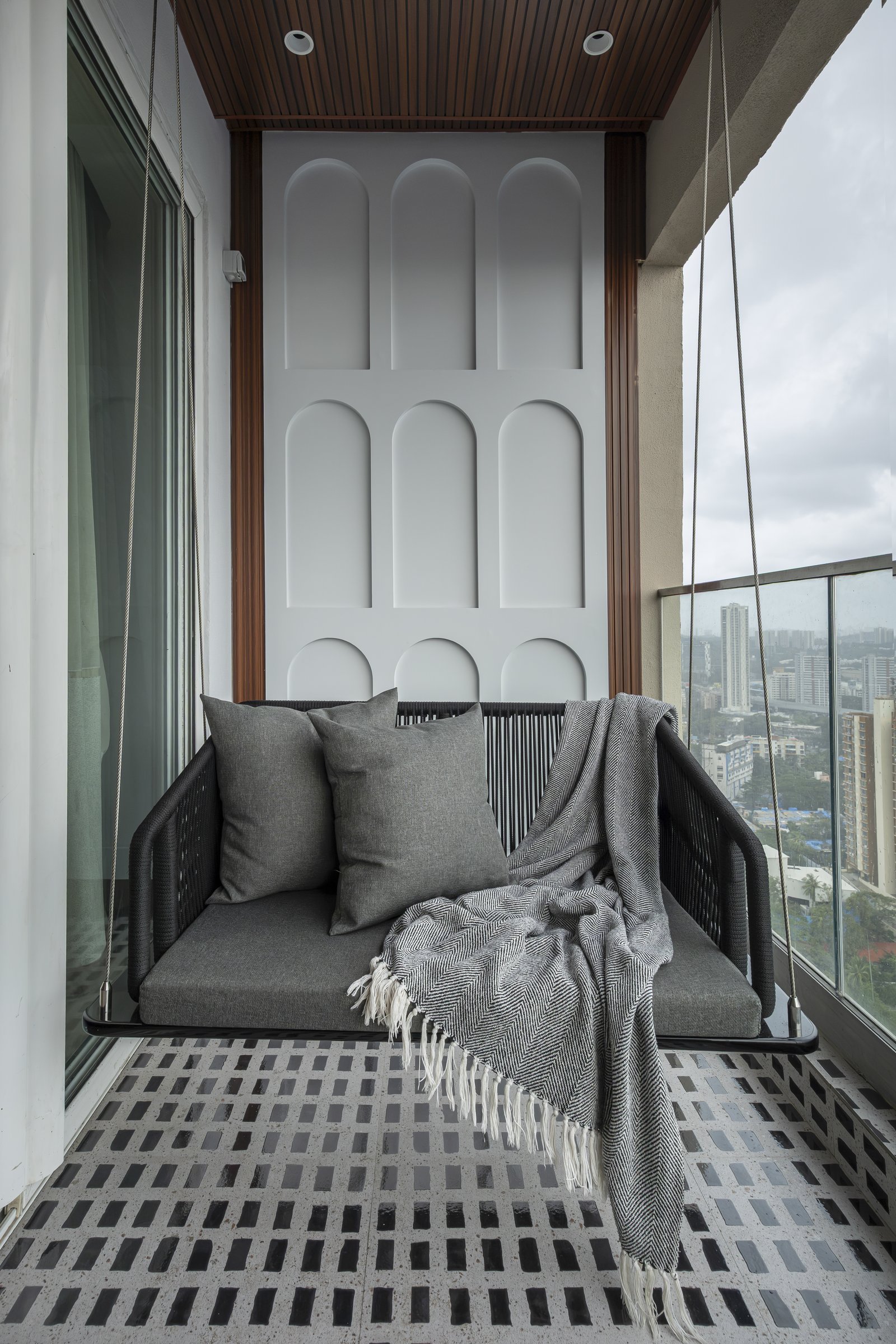 The balcony, where a moulded wall of arched reliefs forms the backdrop to a dark woven rope swing