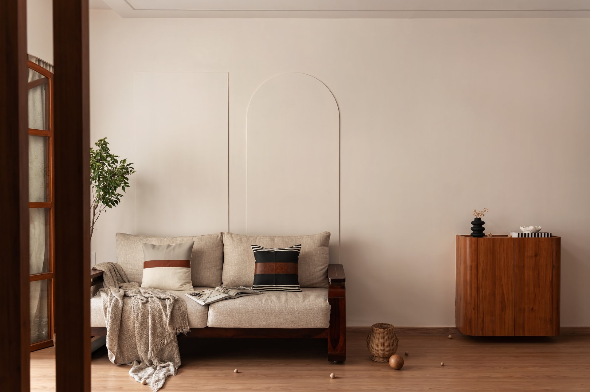 A wider view of the living room, the arched wall pairing with a curved wooden sideboard opposite