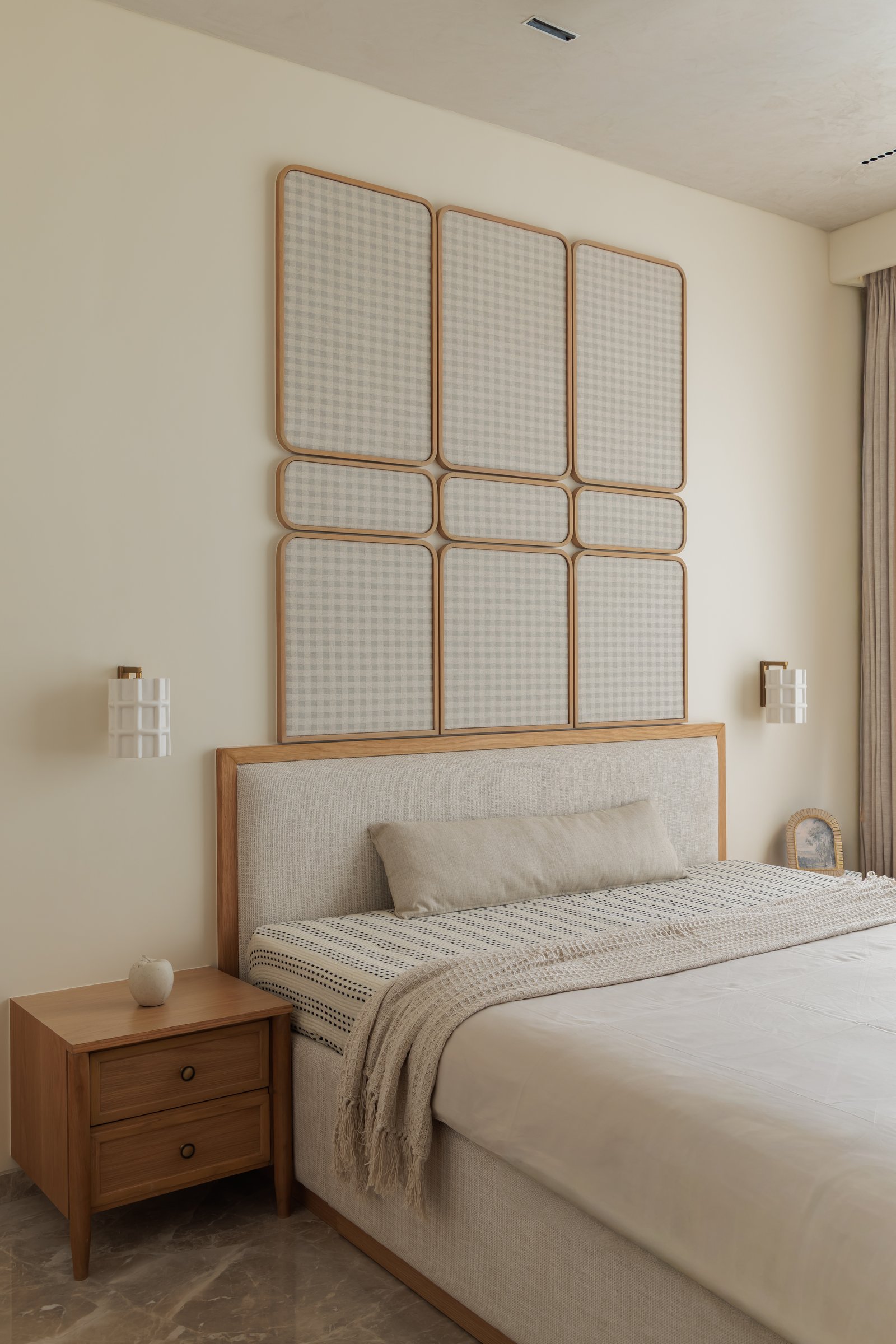 The second bedroom, where a nine-panel gingham-filled grid floats above an upholstered headboard