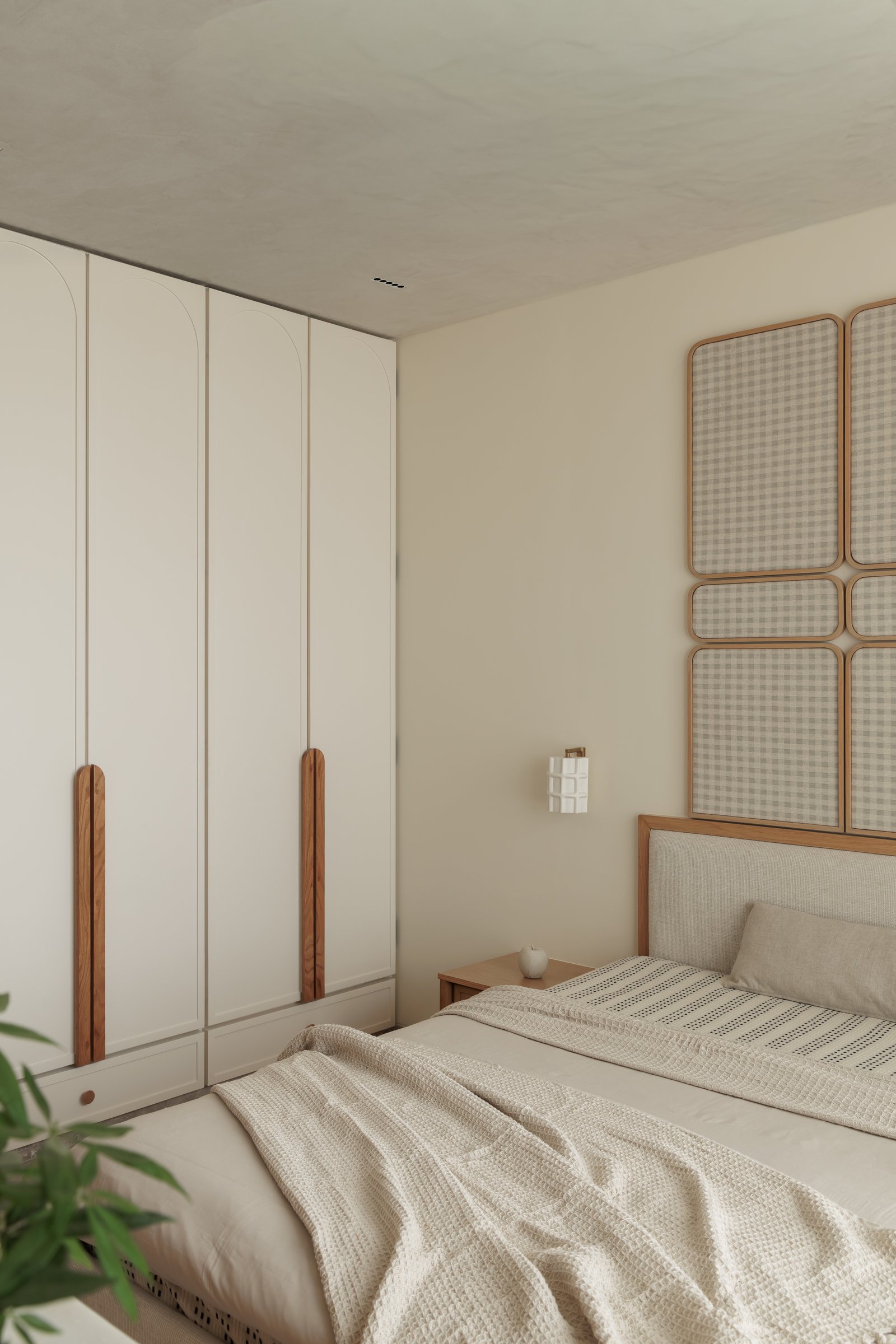 Pale lime-plaster ceilings and tall arched wardrobes with carved wooden handle pilasters quiet the room