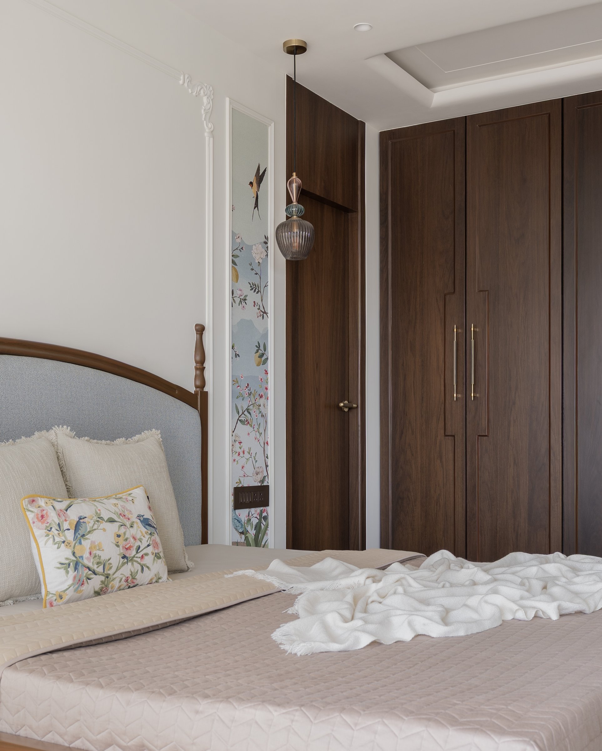 The master bedroom's panelled wardrobe wall in walnut-toned wood with slender brass-and-wood pulls