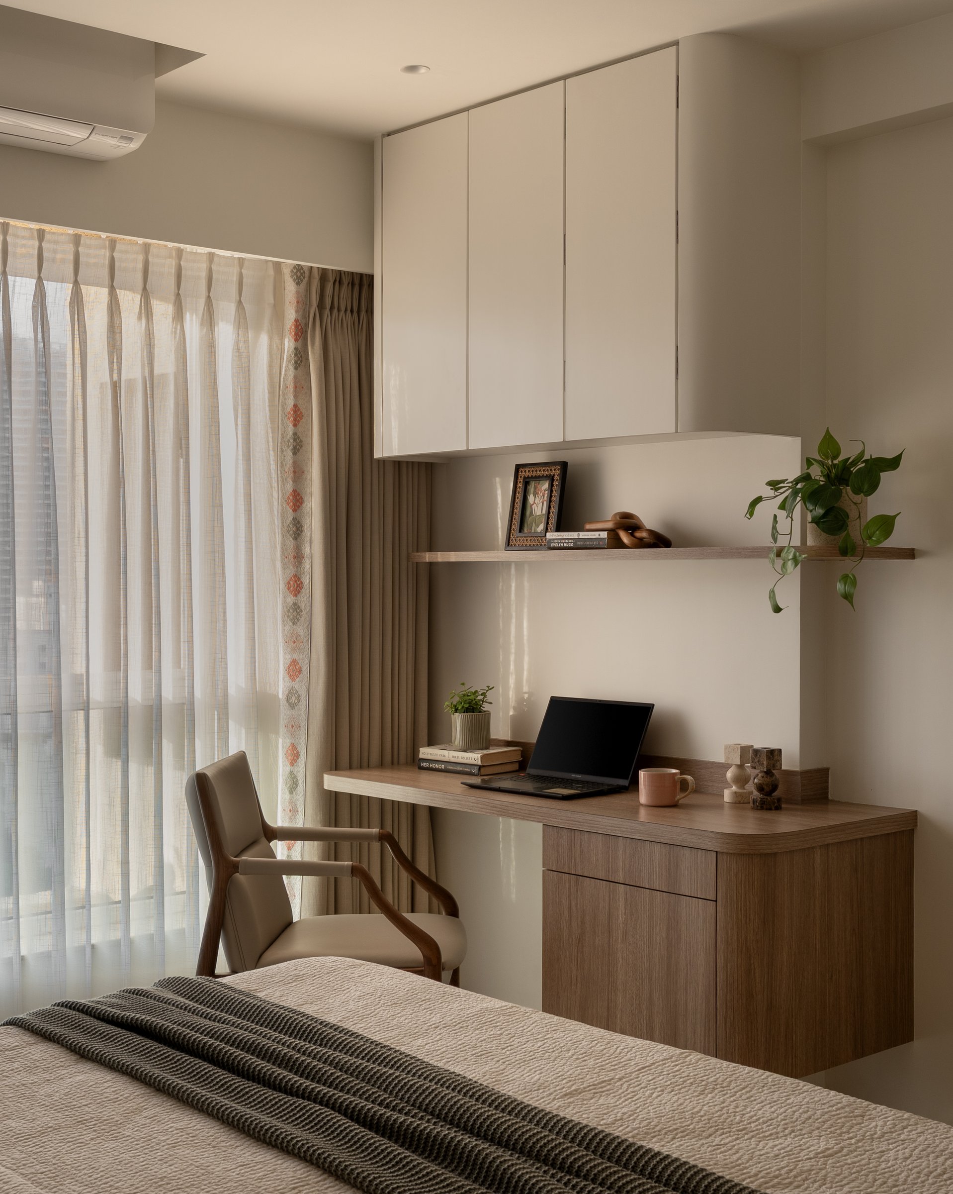 A compact study nook folded into the second bedroom, with wooden desk and overhead storage