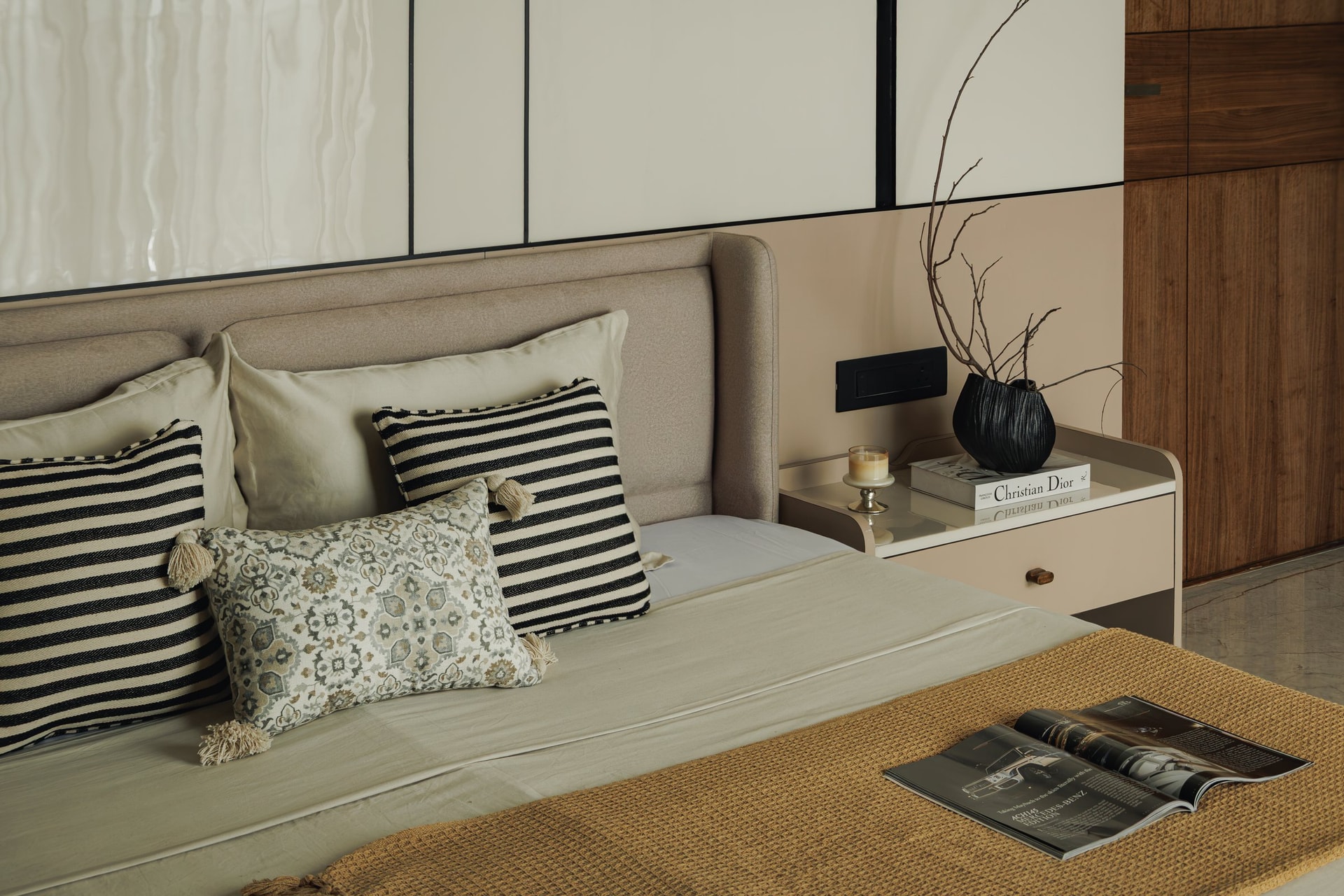 The bed wall at closer range, with an upholstered headboard meeting panelled inserts and a bedside console in soft beige