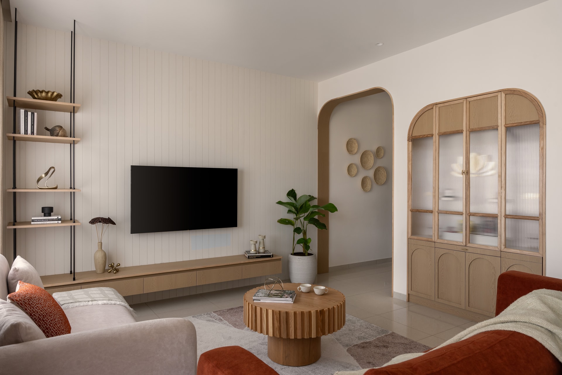 Living room with fluted wood paneling, arched doorway, and terracotta accent sofas