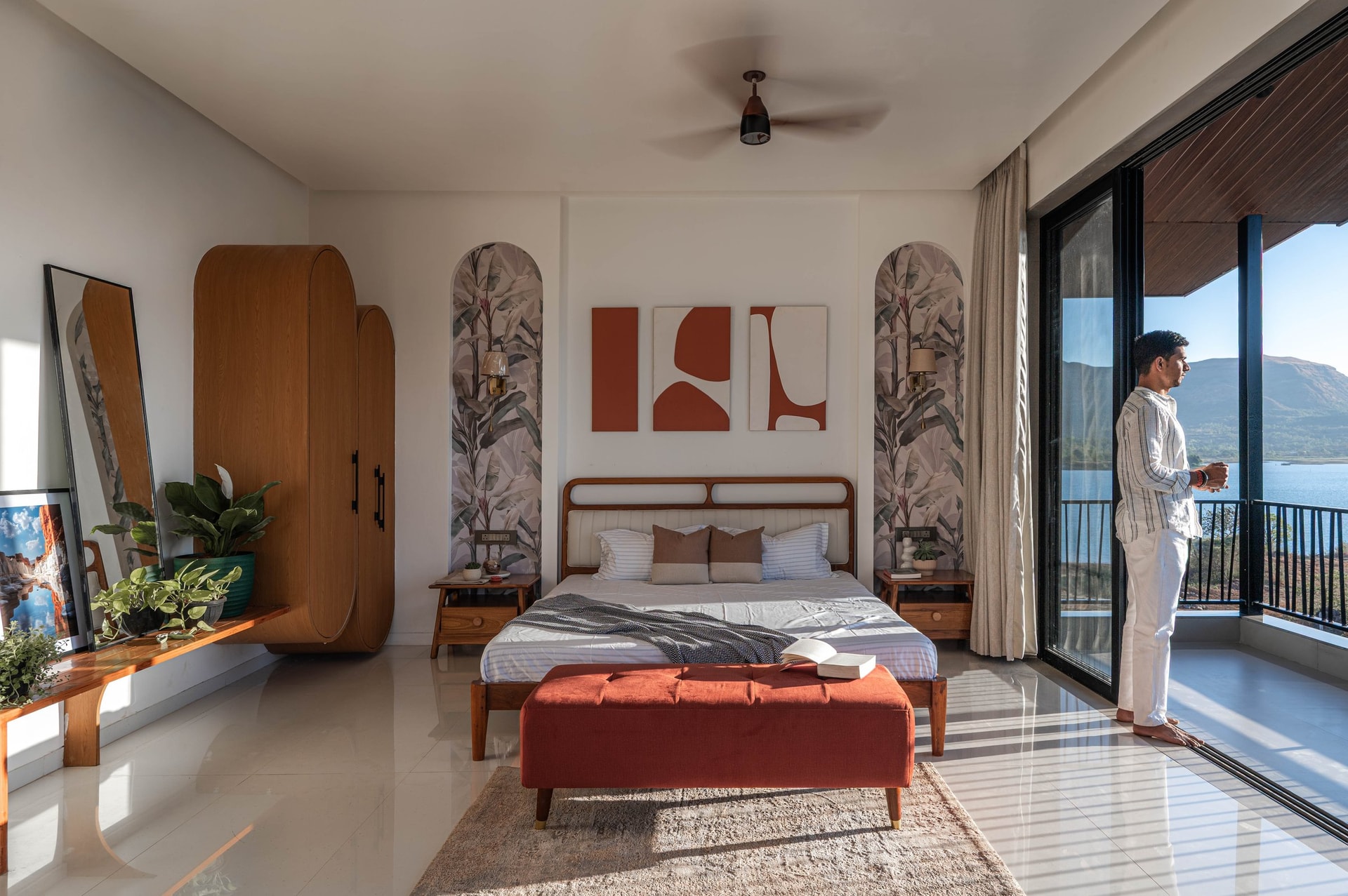 The master bedroom opens fully to Pawna reservoir, with arched botanical niches flanking the bed