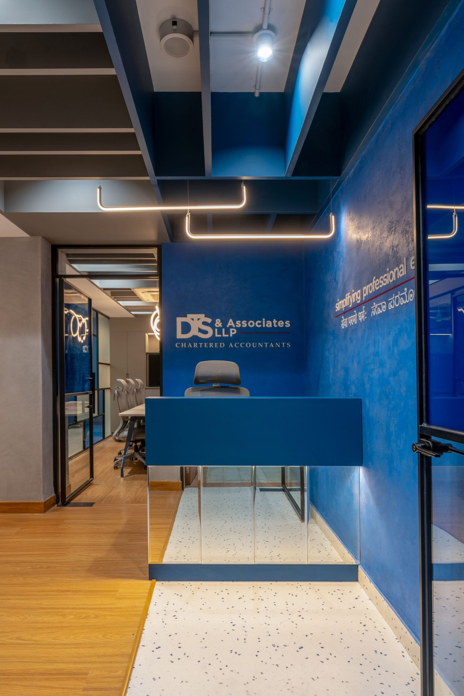 The reception: a lime-plastered indigo wall and terrazzo floor establish the project's restrained palette before a visitor has fully arrived