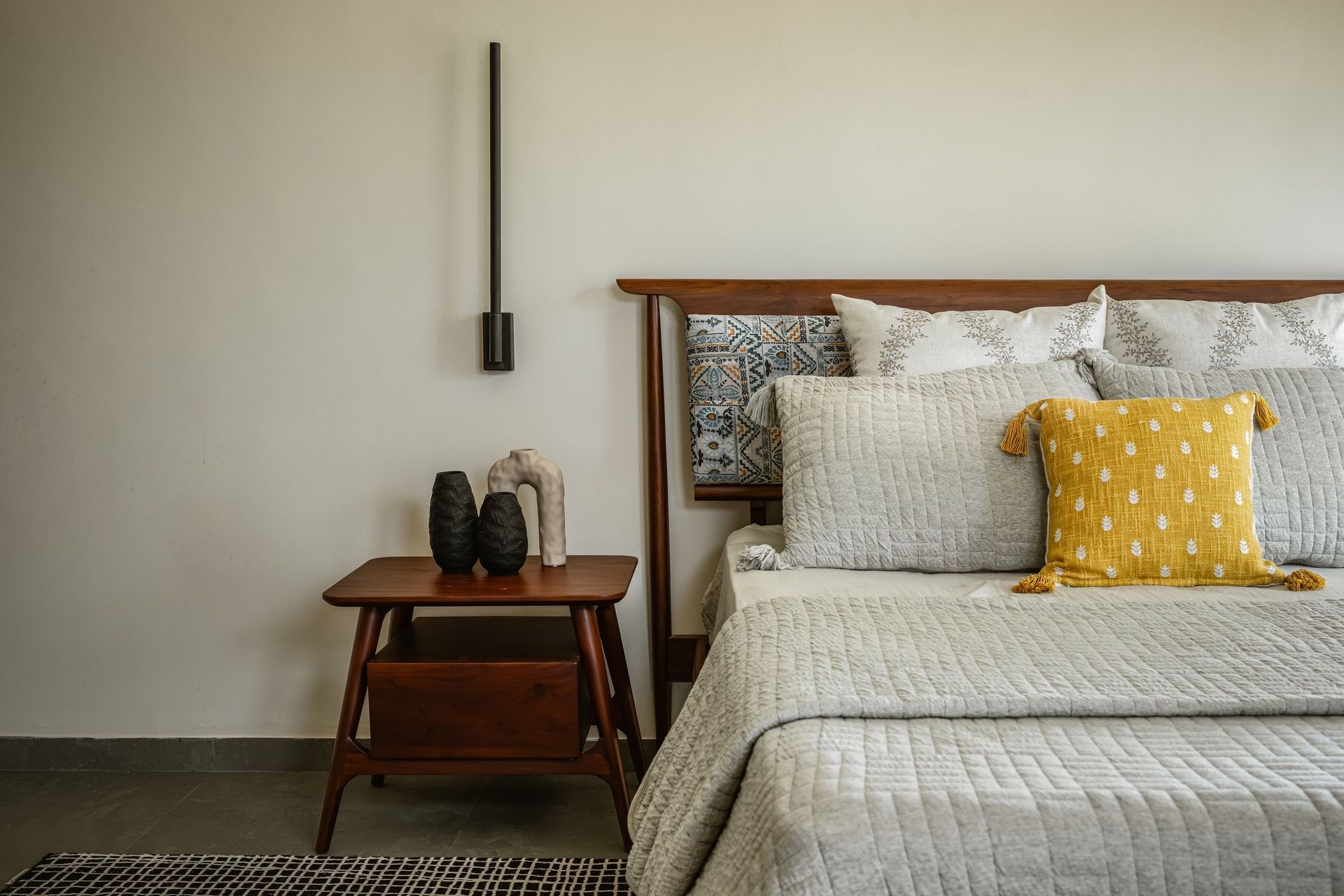 A patterned ceramic inlay set into the wooden headboard carries the encaustic language of the public rooms into the private zone