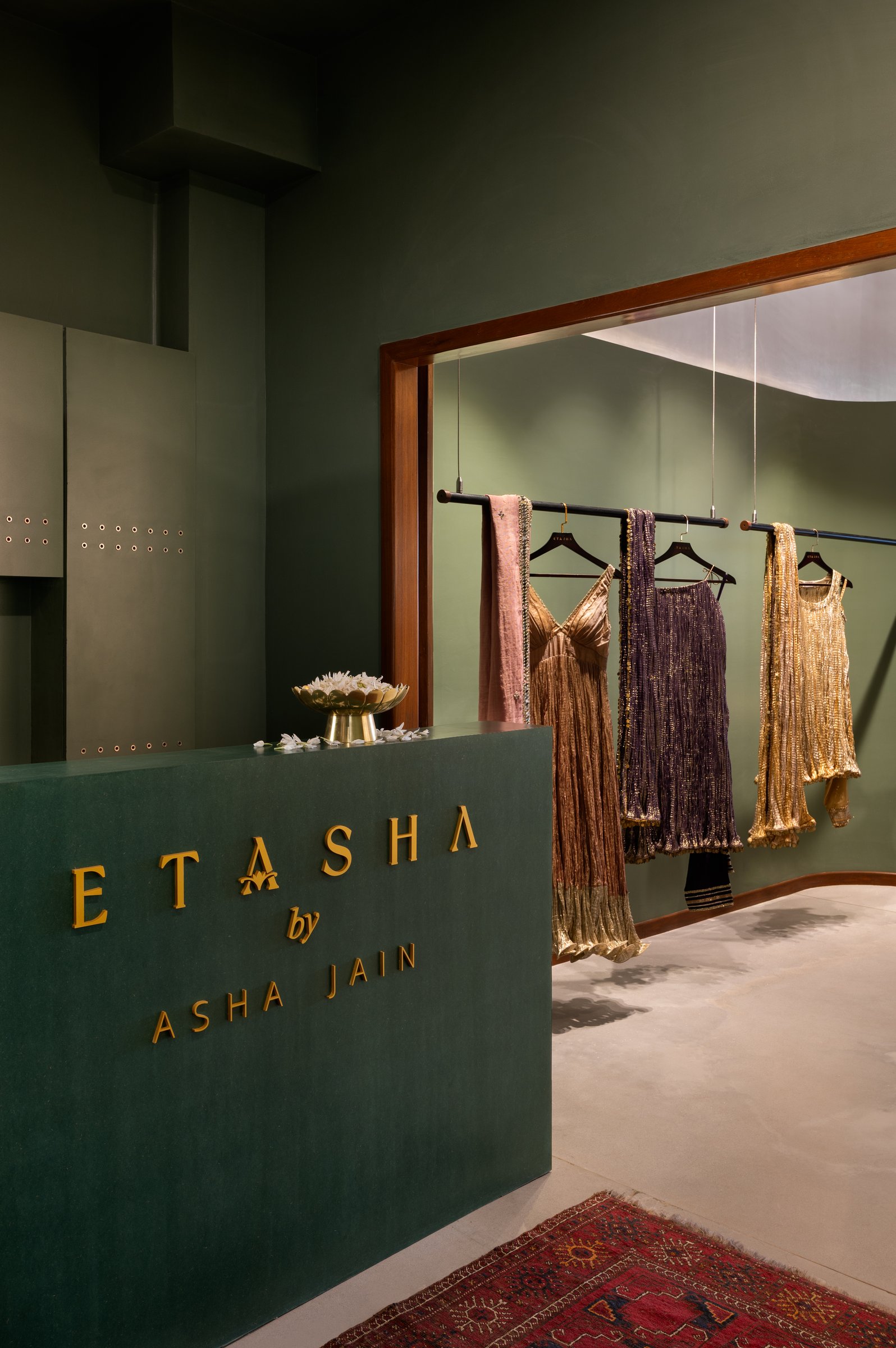 The reception desk in matte green pigmented putty, where brass lettering replaces the gloss one might expect from luxury retail