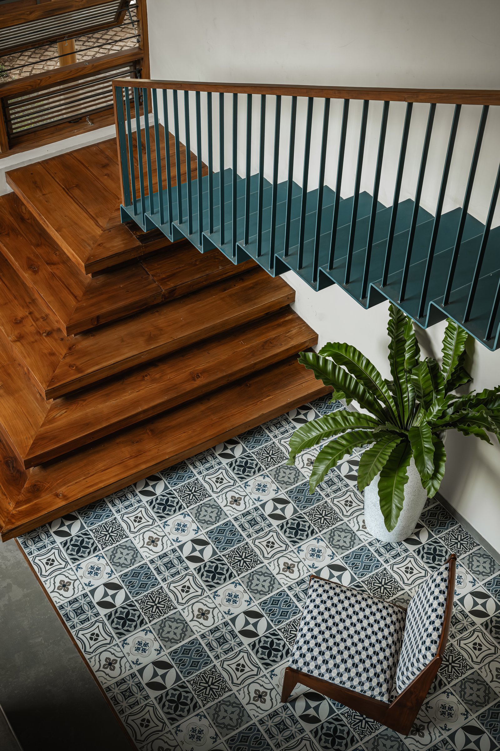 Seen from above, the staircase reveals its full geometry against the encaustic tile expanse that anchors the architecture throughout