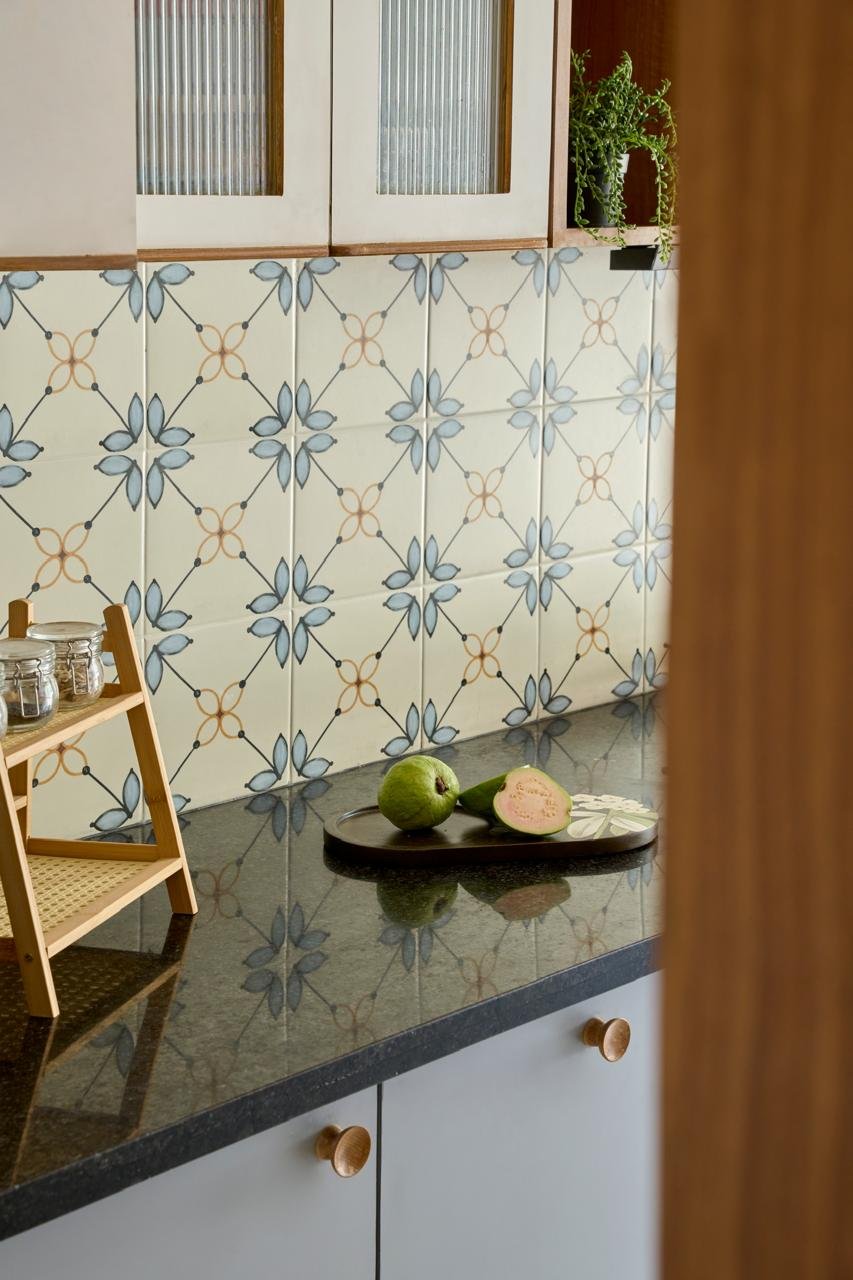 The backsplash up close: a repeating four-petalled motif in pale blue and warm orange on an off-white ground