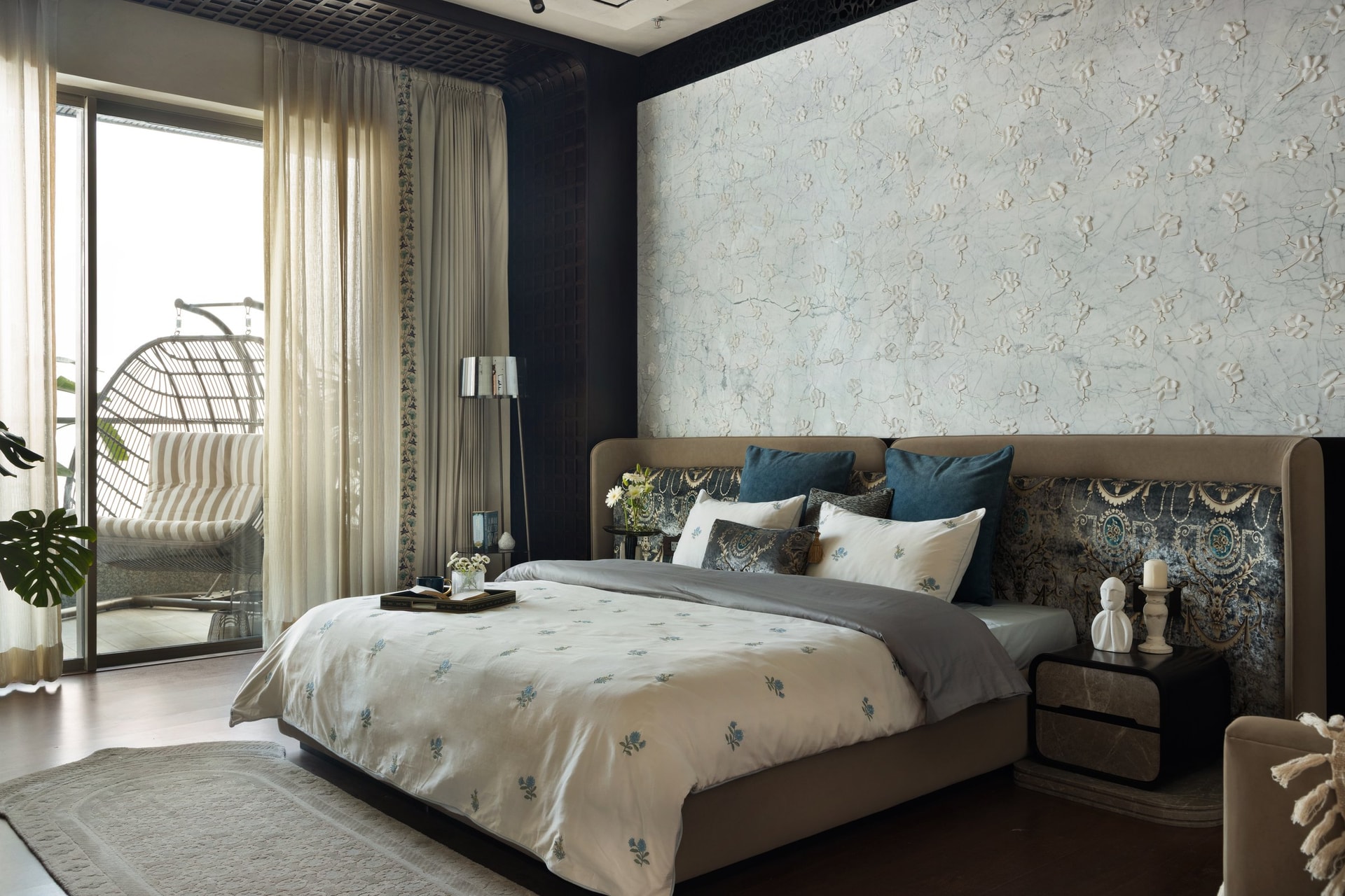 The master bedroom, where a textured floral wall and a dark wood lattice screen frame the upholstered headboard