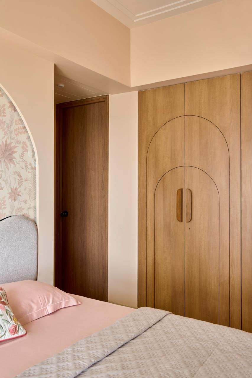 The wardrobe wall in the master bedroom, its double-arch inlay echoing the home's broader curved vocabulary