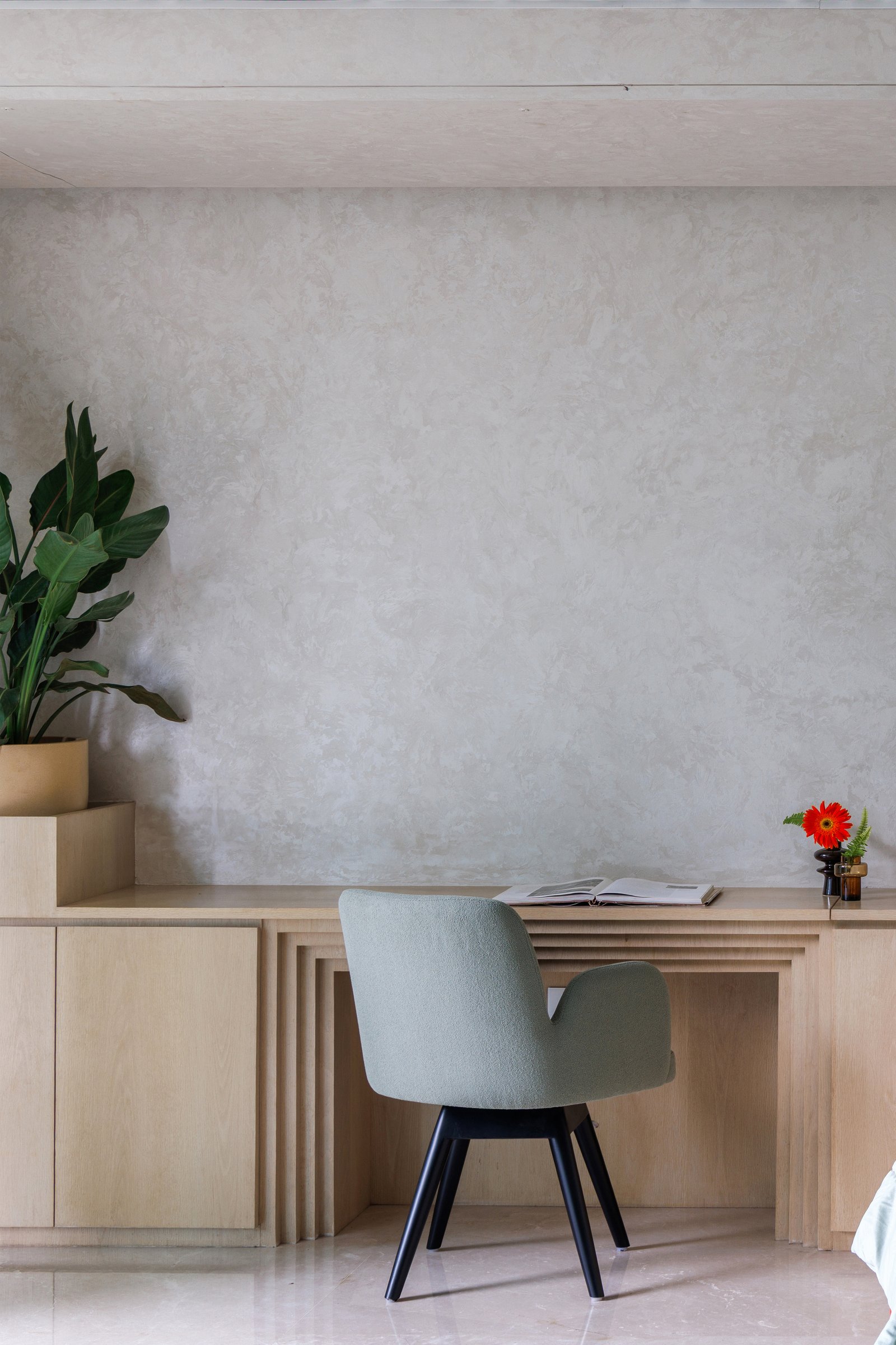 In the principal bedroom, a built-in writing desk extends from a low cabinet run, its stepped fluted edge citing the foyer door