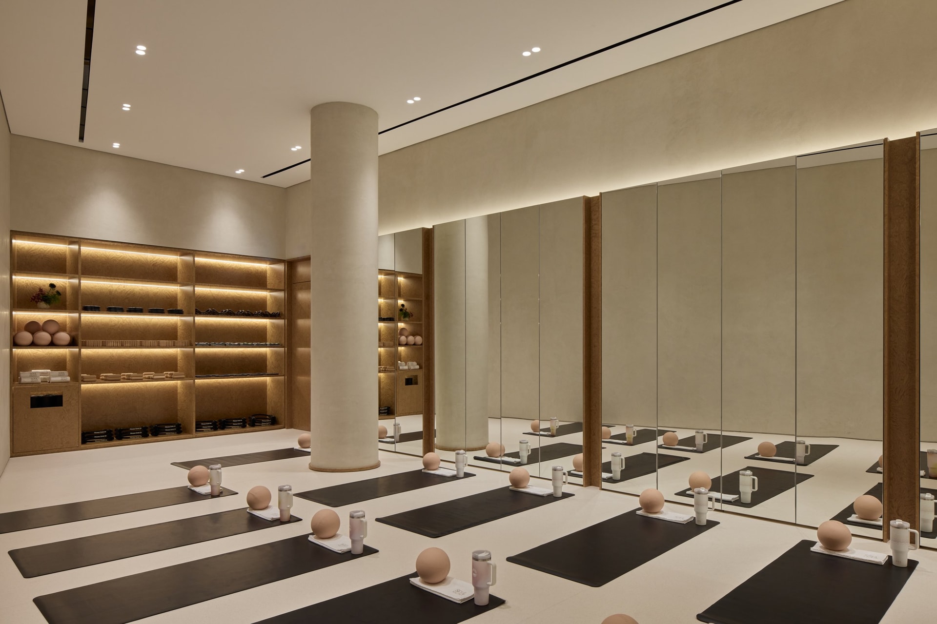 The mat studio, defined by a backlit burl wood shelving wall and a long mirrored elevation