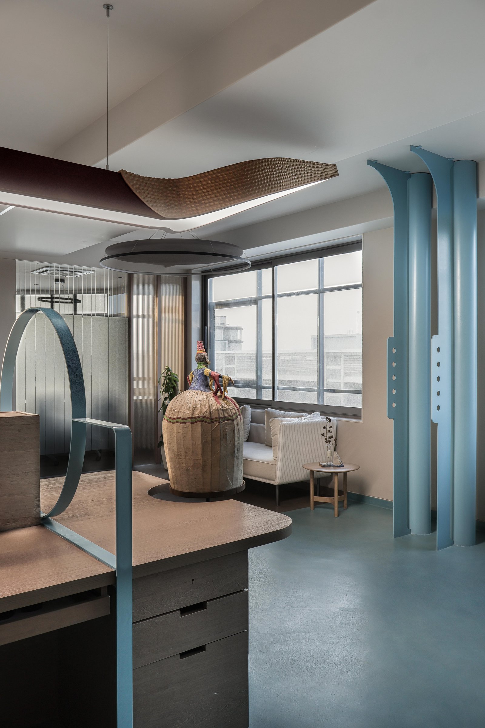 Pale cyan columns, perforated mild-steel fins, and a textured ceiling band that softens the corporate register