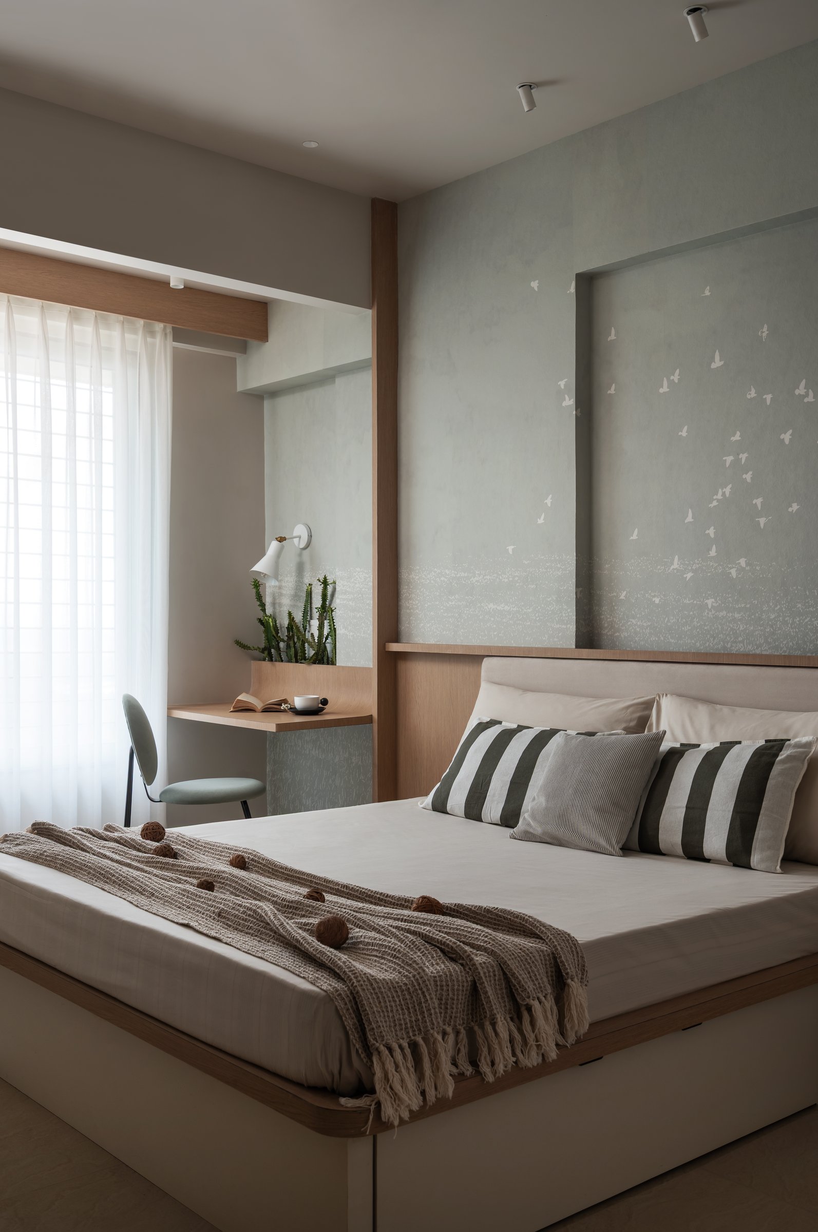 The same room read as horizontals: headboard ledge, desk plane and sheer-curtained window in a single composition