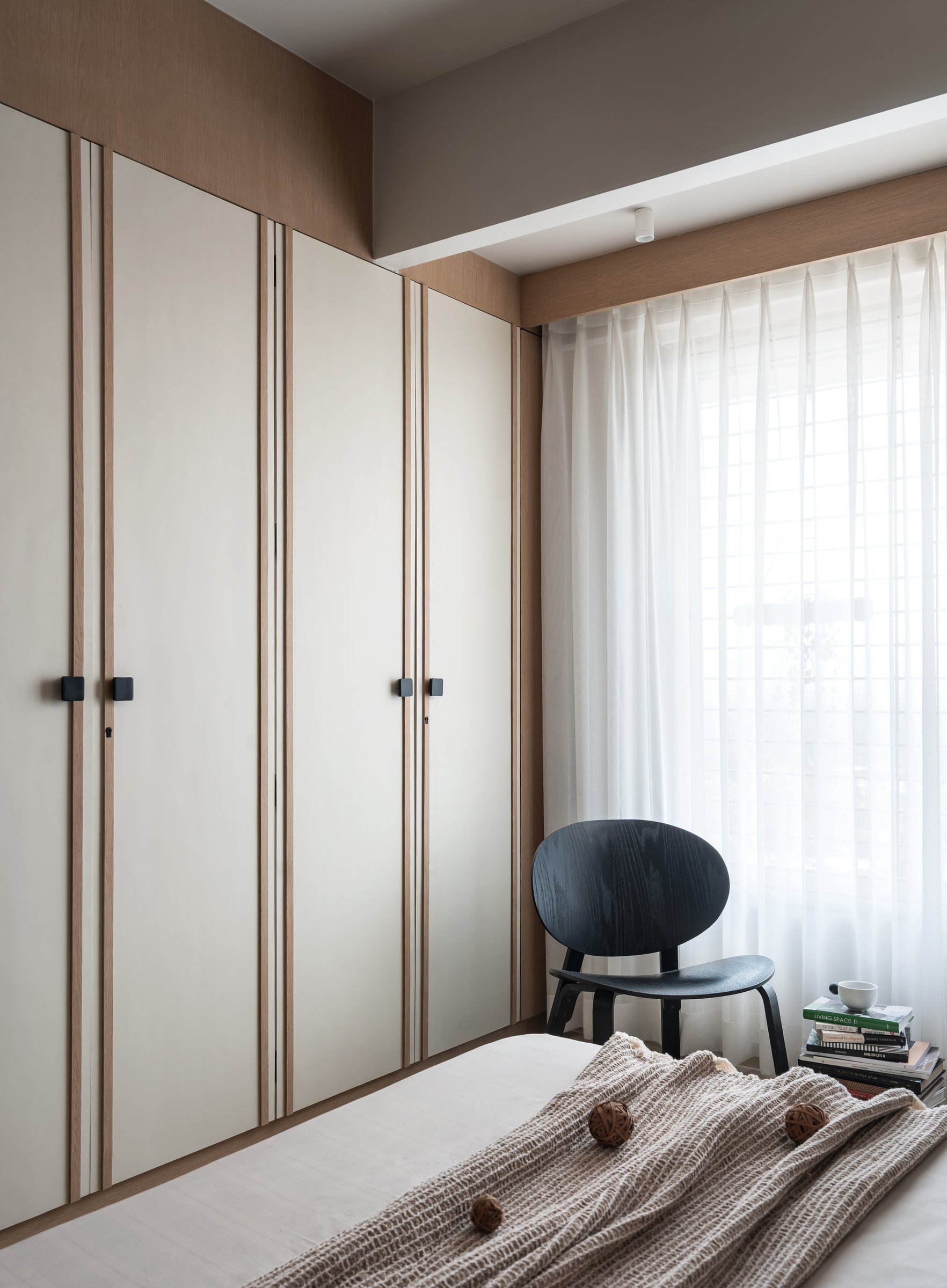 The wardrobe wall, detailed with thin vertical reveals that read as restrained pinstripe rather than ornament