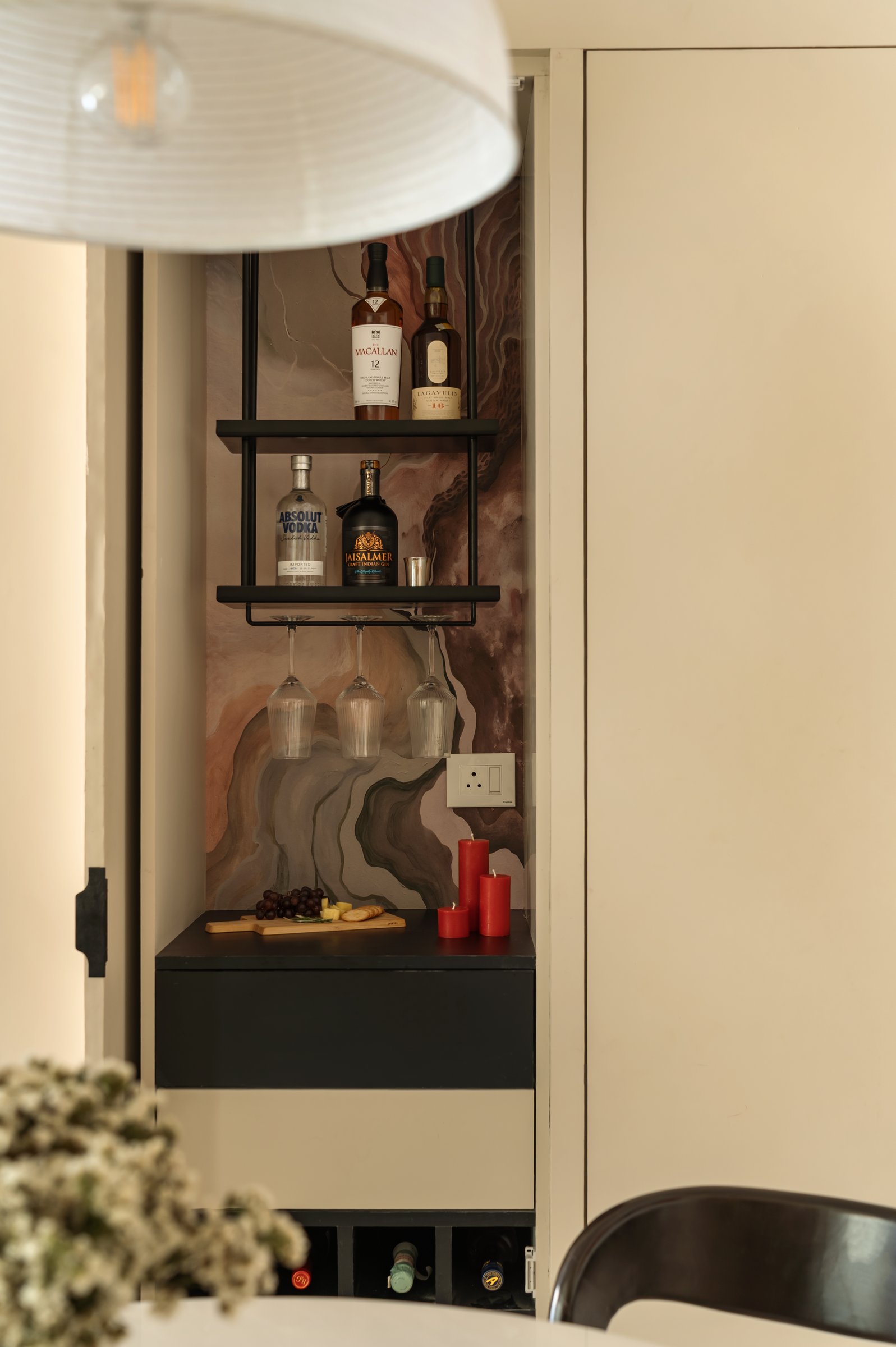 The bar, tucked behind a flush cabinet door and lined with a watercolour-marbled wallpaper