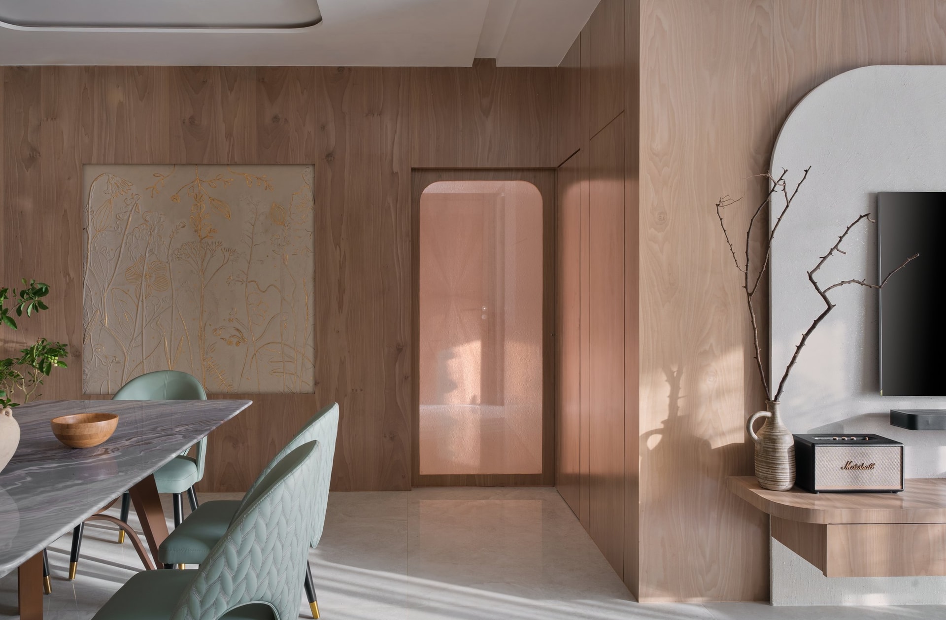 A framed botanical artwork in soft gold anchors the dining room's wood-clad volume