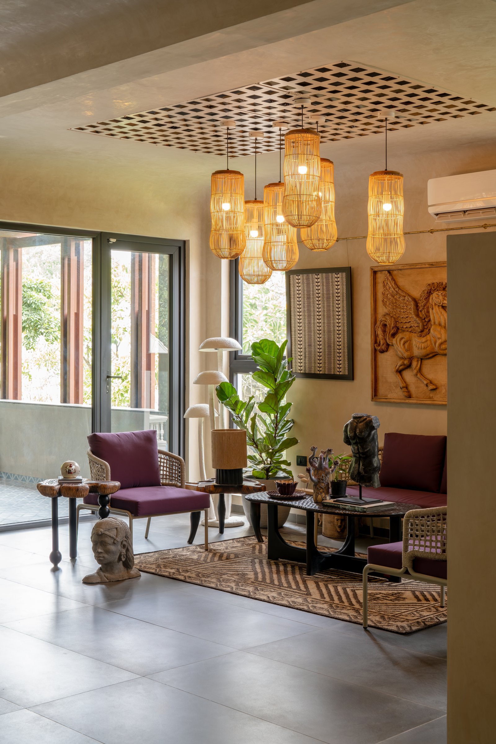 A seating vignette beneath a cluster of cane pendants, framed by a ceiling cut-out lined with a woven screen
