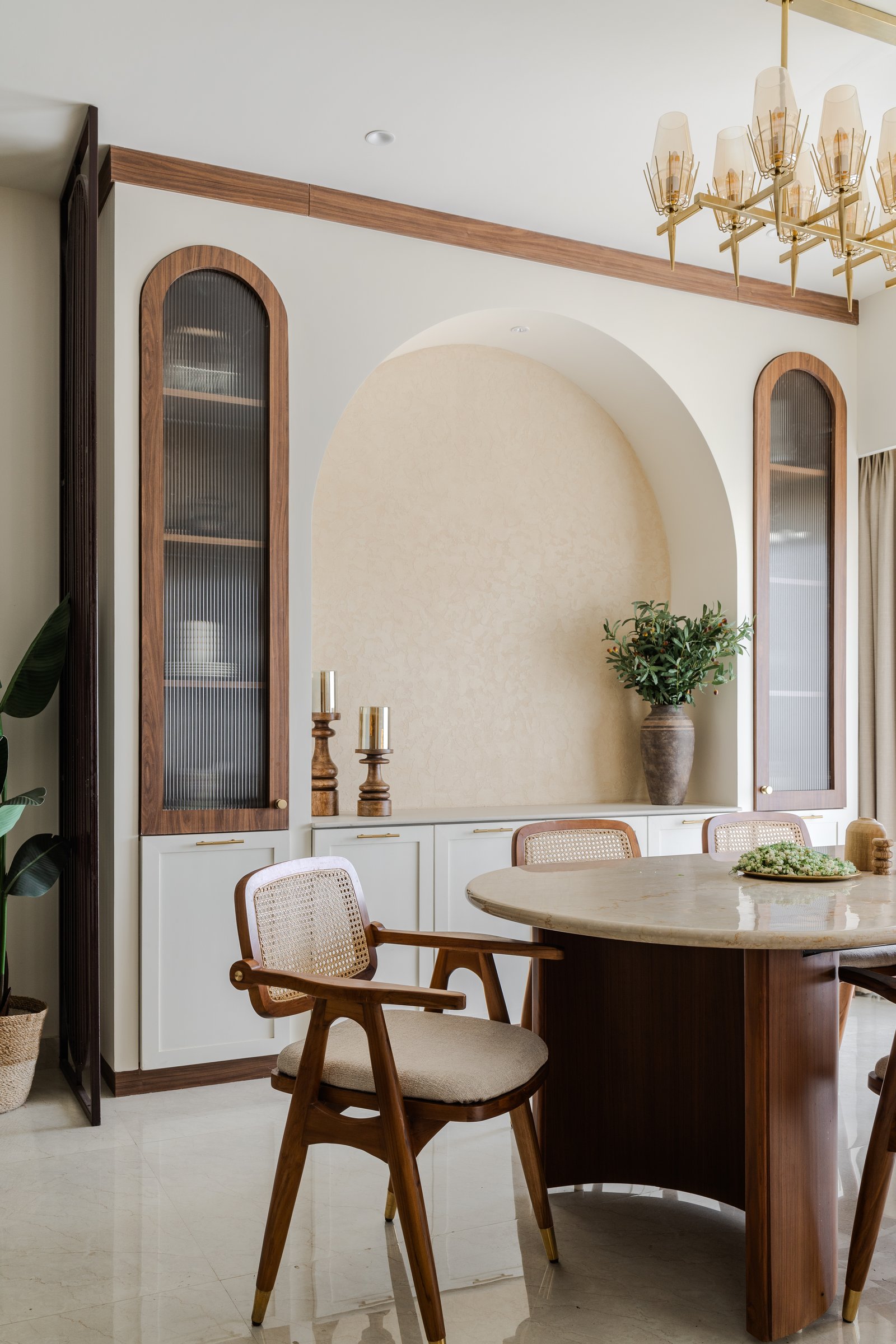 The dining alcove: a textured plaster arch flanked by two tall fluted-glass cabinets, edited down to a clay vessel and two candleholders