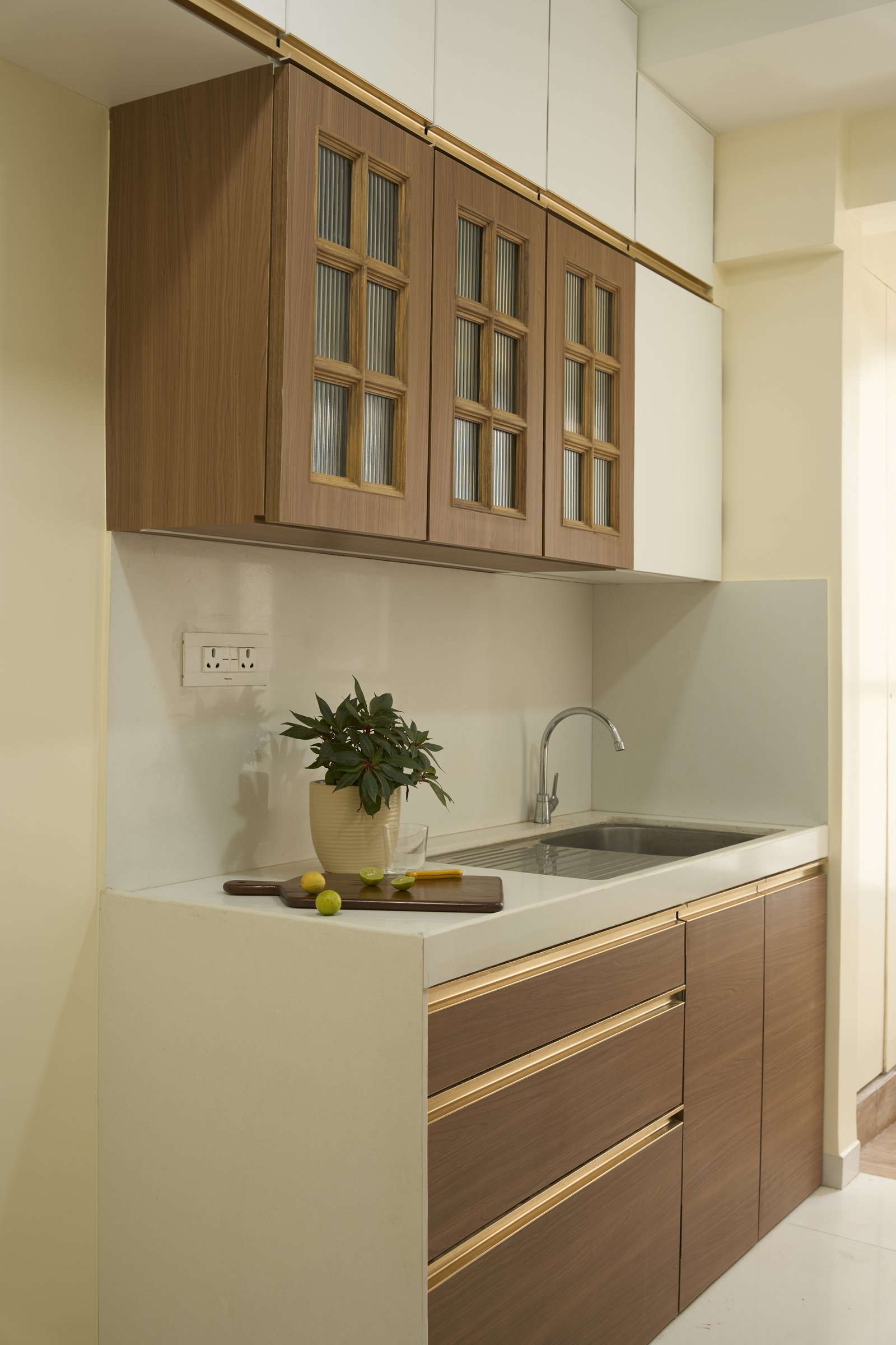 The kitchen's upper cabinetry, where fluted glass shutters set within wood frames carry a quietly vintage register