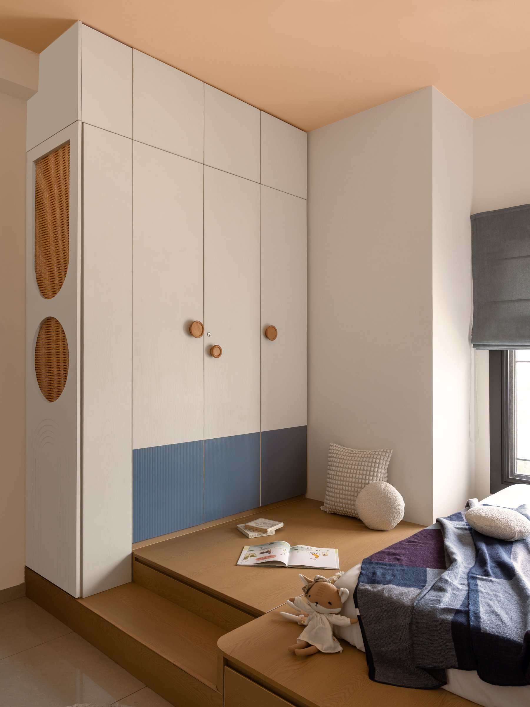 Fluted steel-blue and cream joinery frame the platform that doubles as bed and reading nook