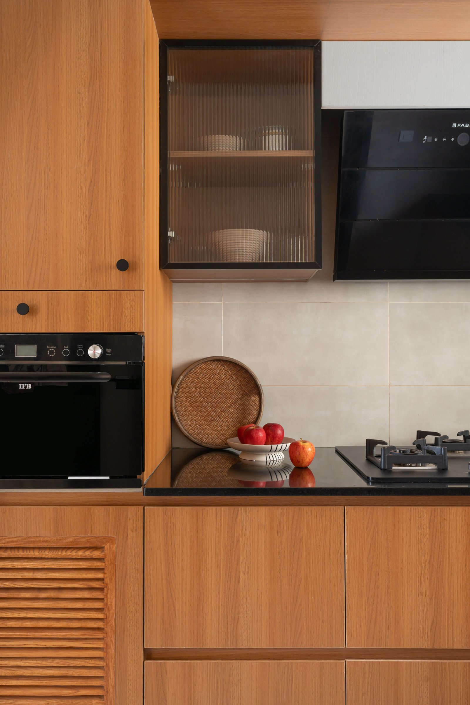 The kitchen: honey-toned cabinetry, black counters, and fluted glass uppers