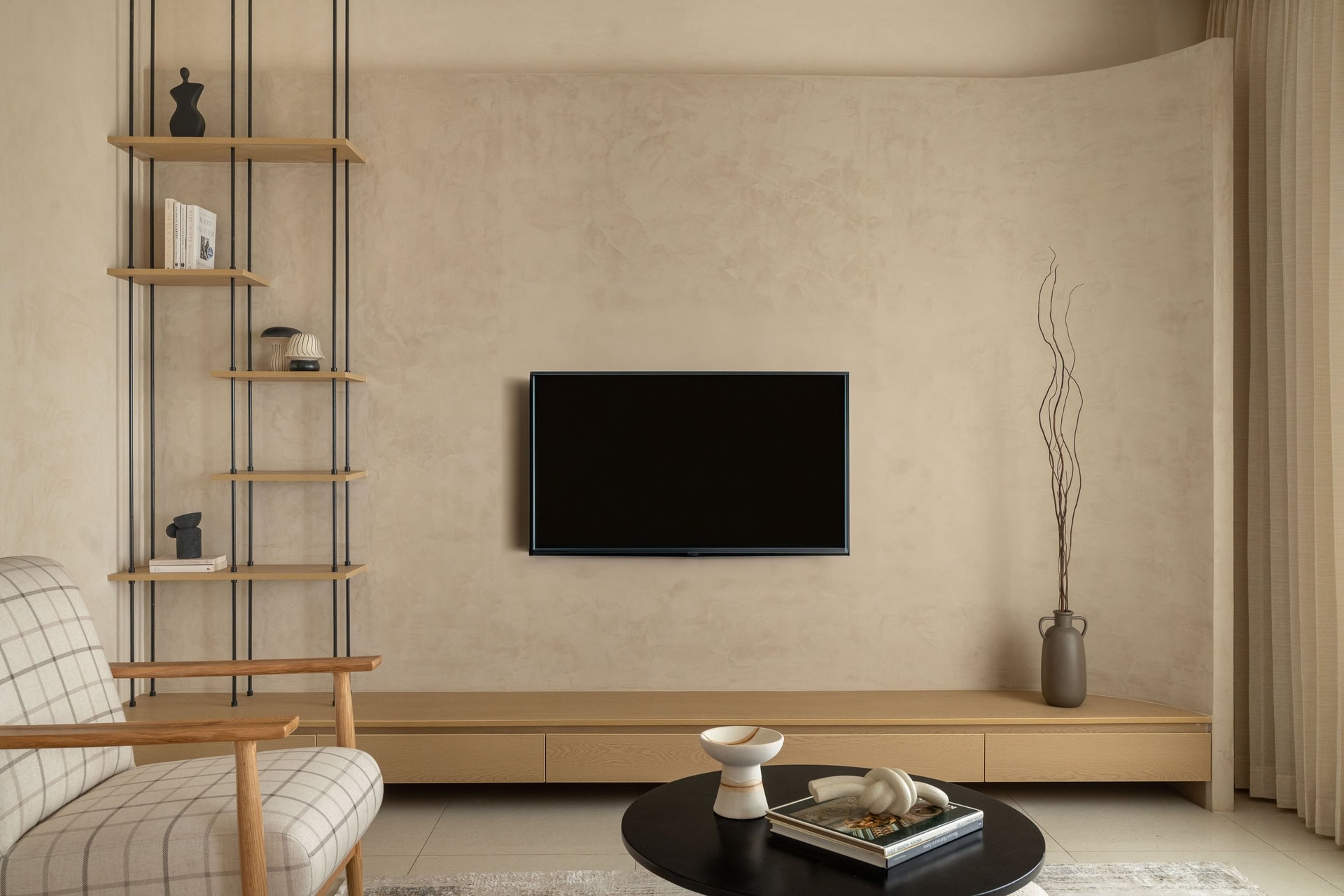 Against the lime-washed wall, floating oak shelves and a low console hold the room's restraint together