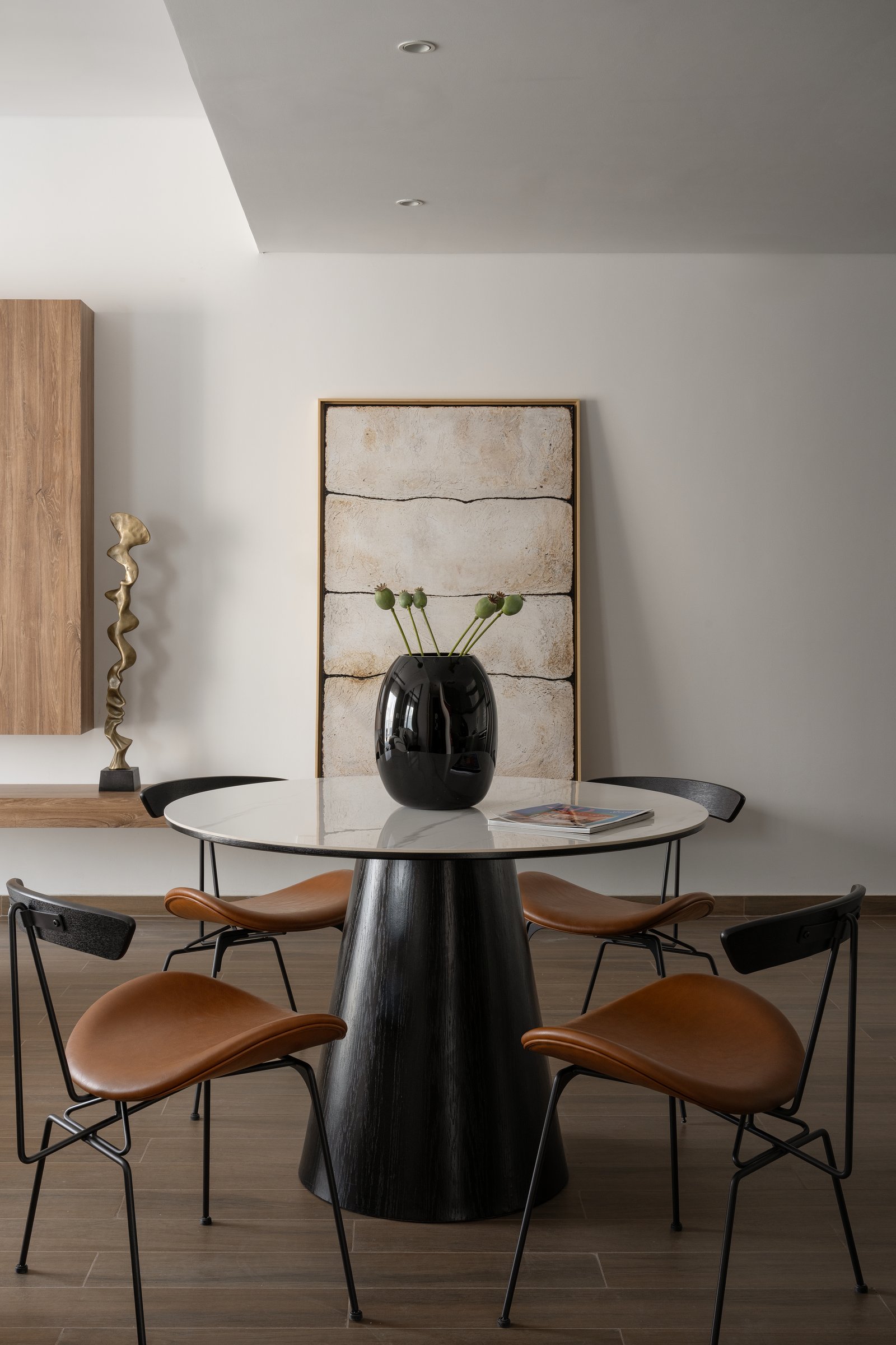 The dining area, where tan saddle-leather chairs and a black pedestal table read as a still life that happens to seat four