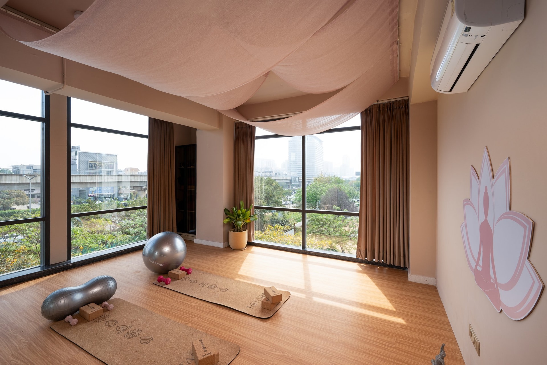 Daylight in the movement studio, where two corner walls of glazing meet the filtered light of the linen canopy above