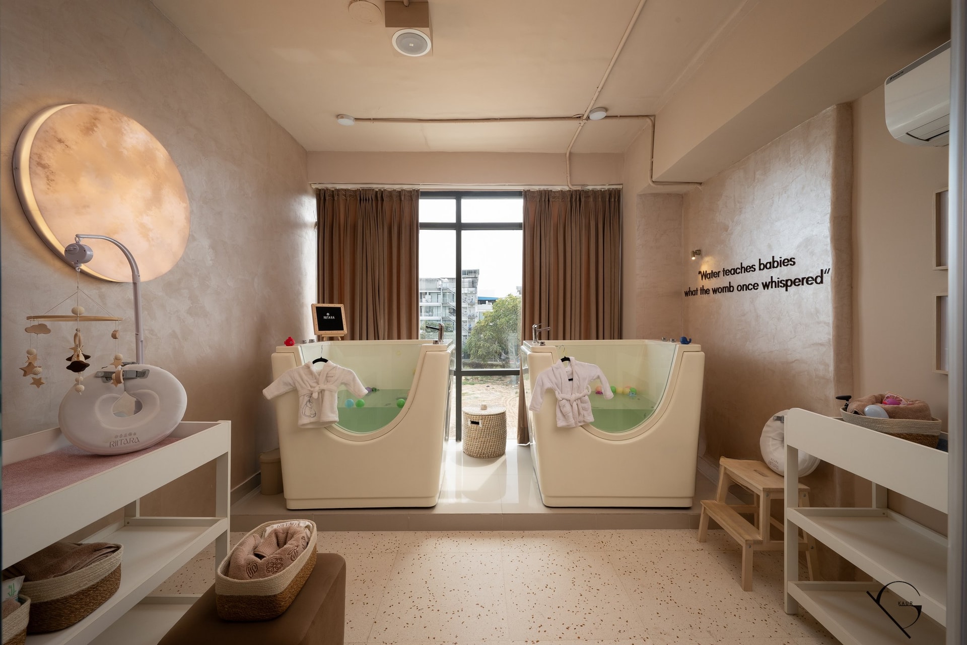 The Aqua Nest: two cream baby hydrotherapy pools sit beneath a softly glowing disc designed to resemble a clouded moon
