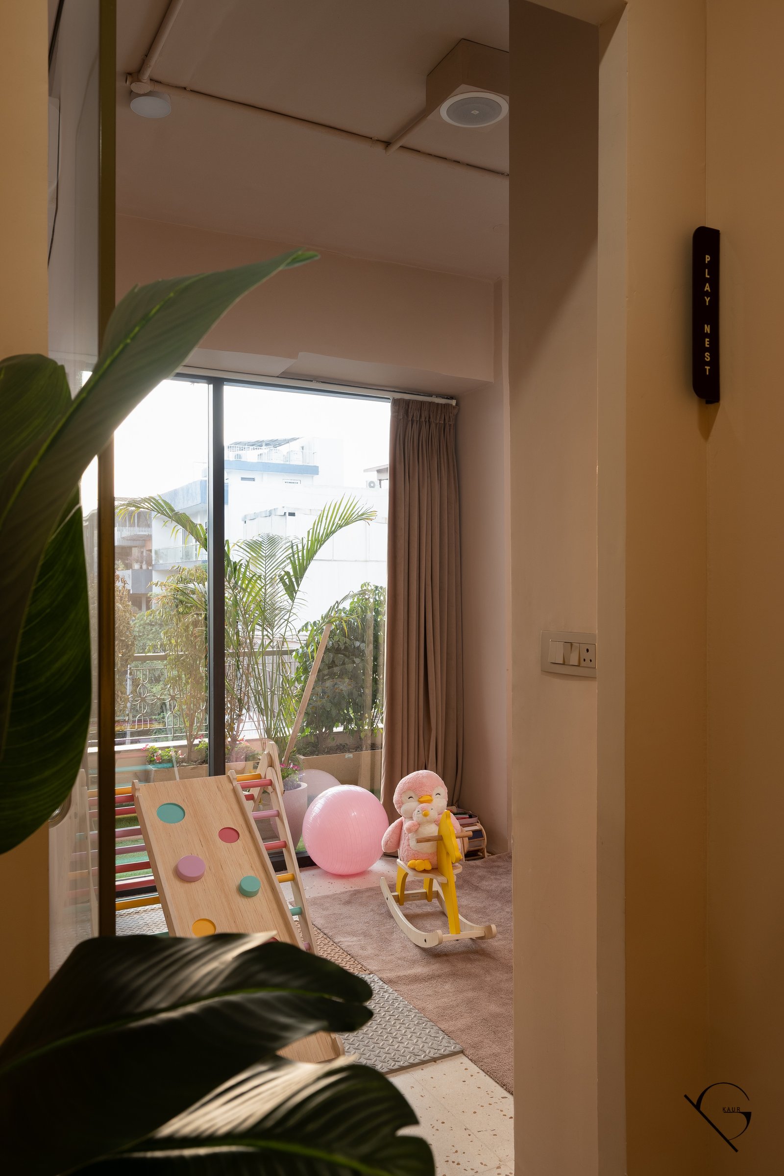 The Play Nest, glimpsed through its signed threshold, where wooden toys and pastel forms occupy a generous rug