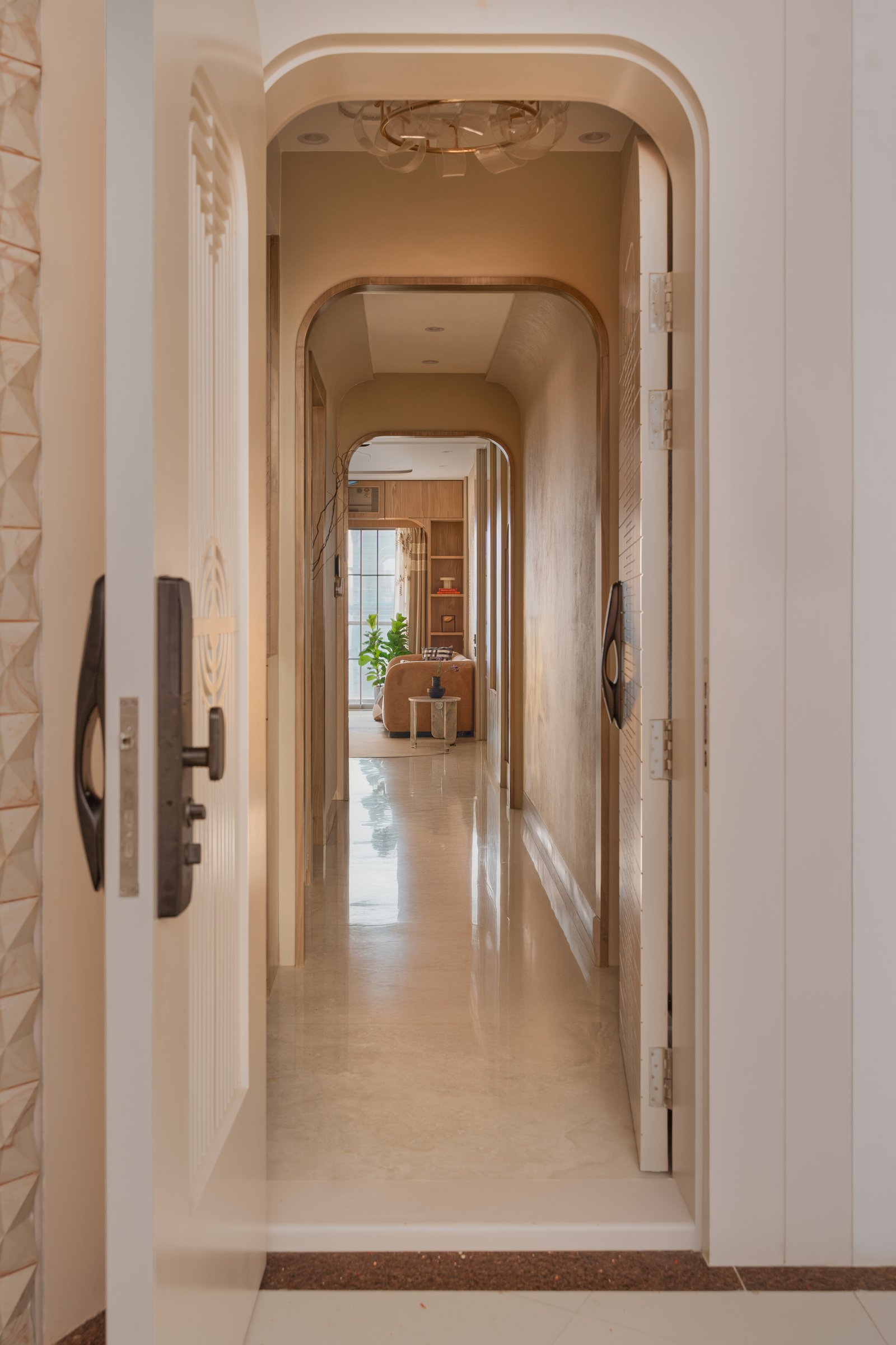 The arched entry corridor frames a sequence of softened portals leading toward the living room