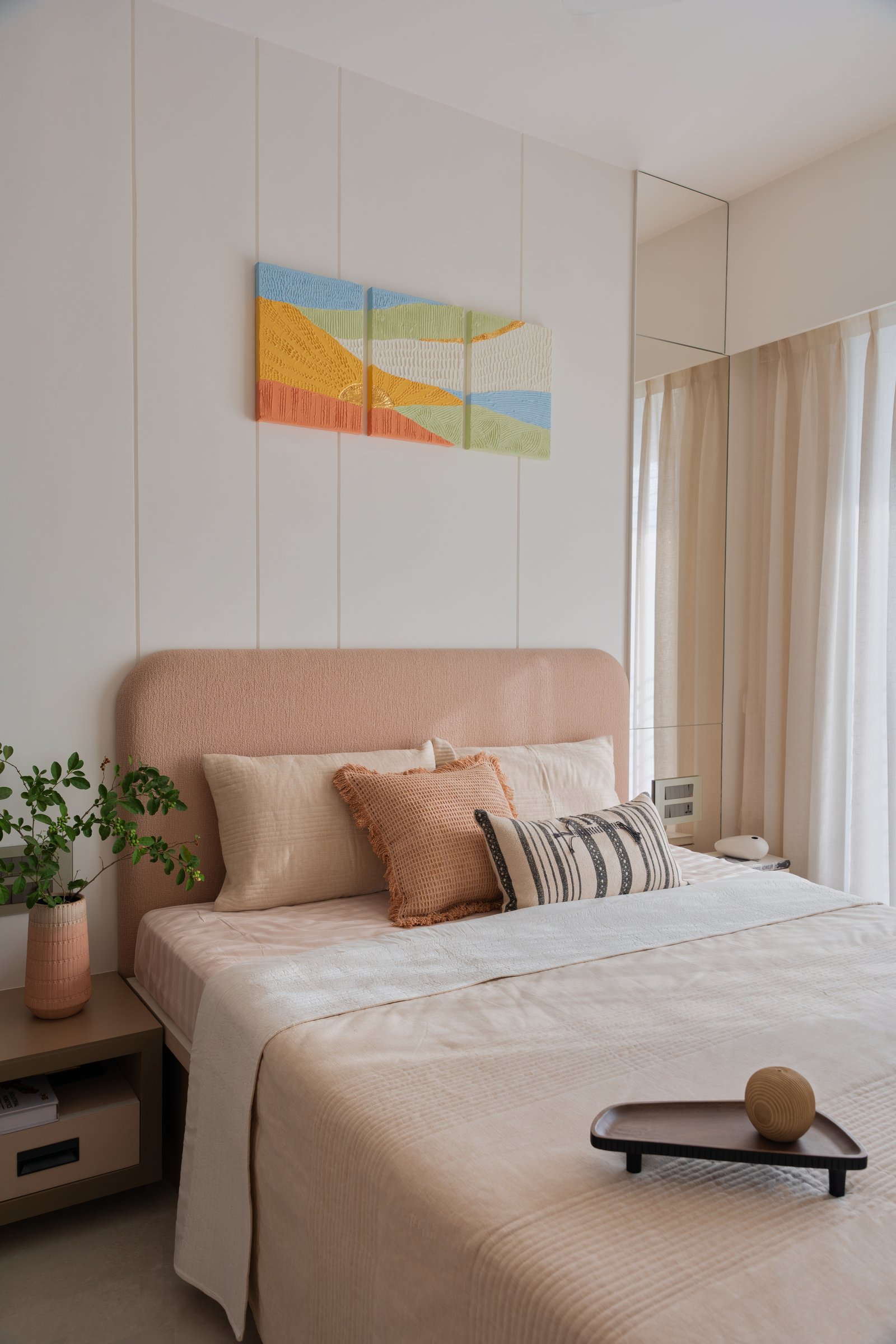 The guest bedroom, organised around a peach headboard and a triptych of textured artworks