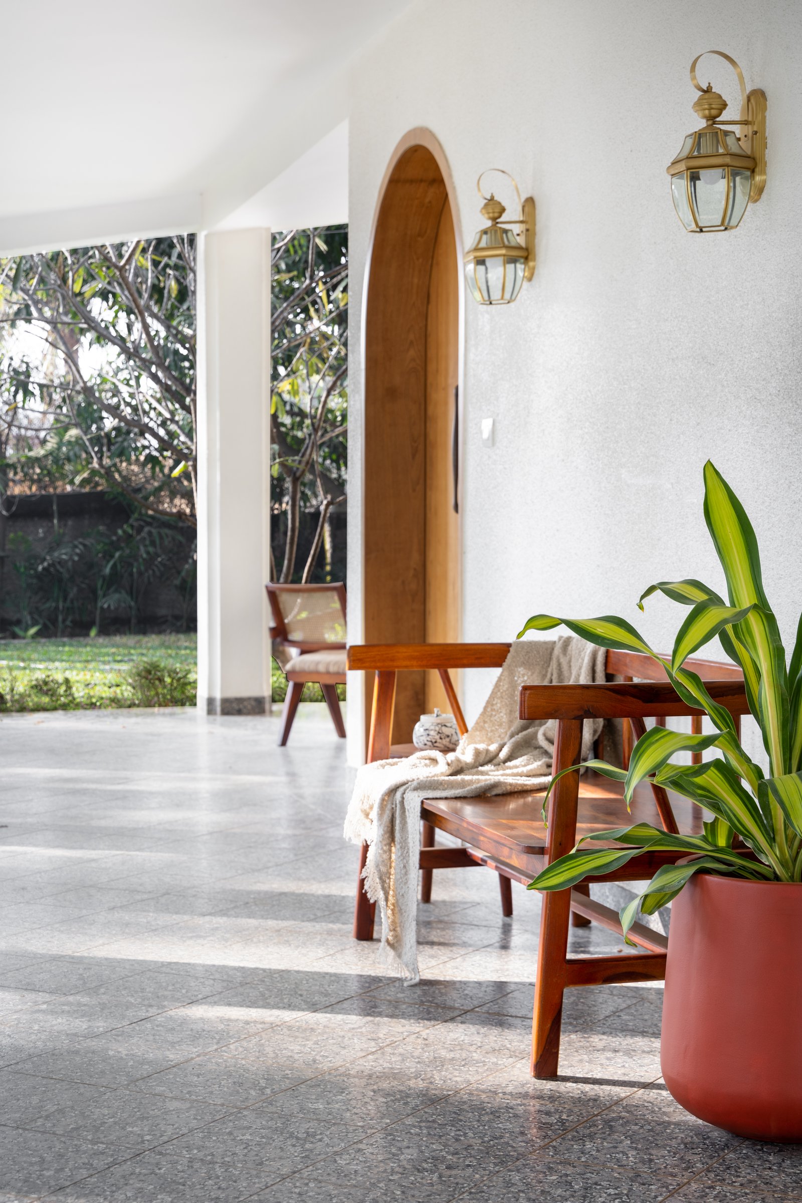 A wooden bench and brass lanterns turn the verandah into a threshold meant to be lingered in