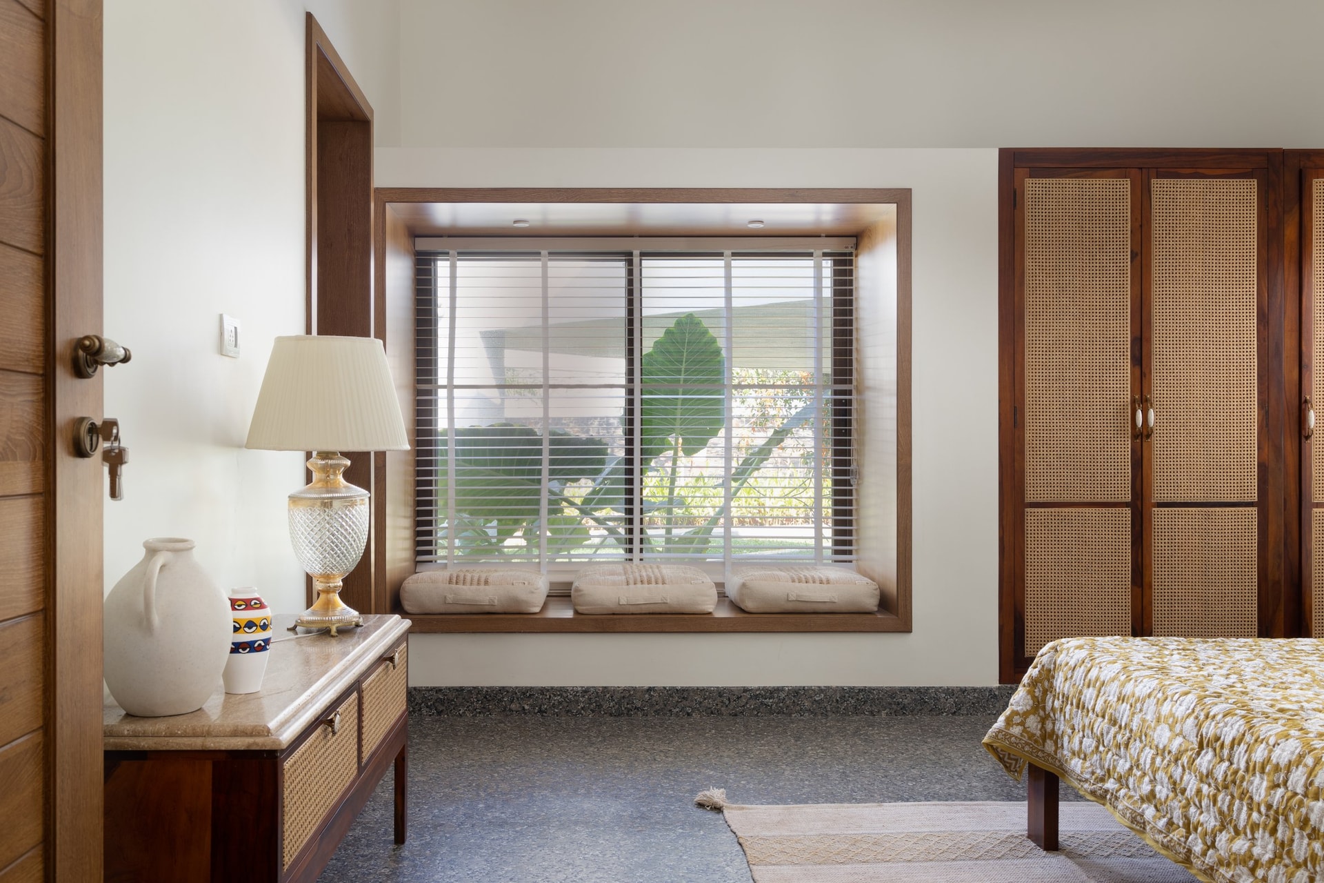 The third bedroom treats its box-window as furniture, with three linen cushions facing the garden through slatted blinds
