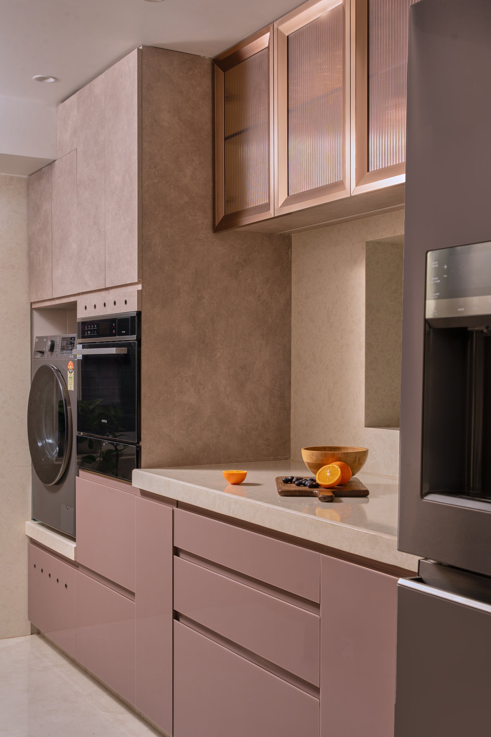 The kitchen in dusty rose, with fluted glass cabinet fronts and a stone-finish upper run