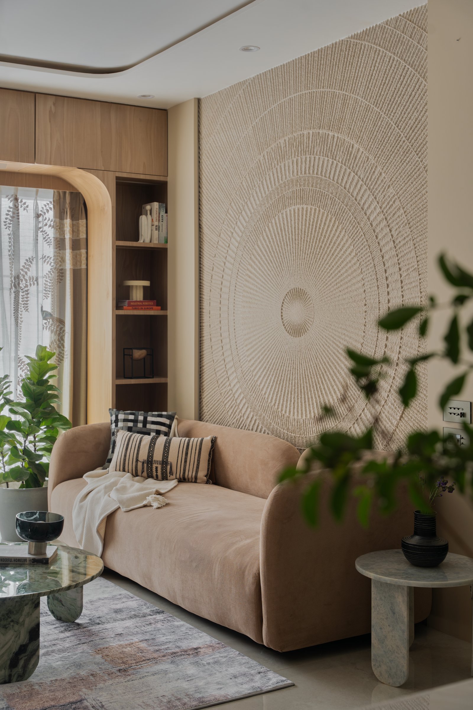 The concentric relief behind the sofa operates as both artwork and acoustic softener