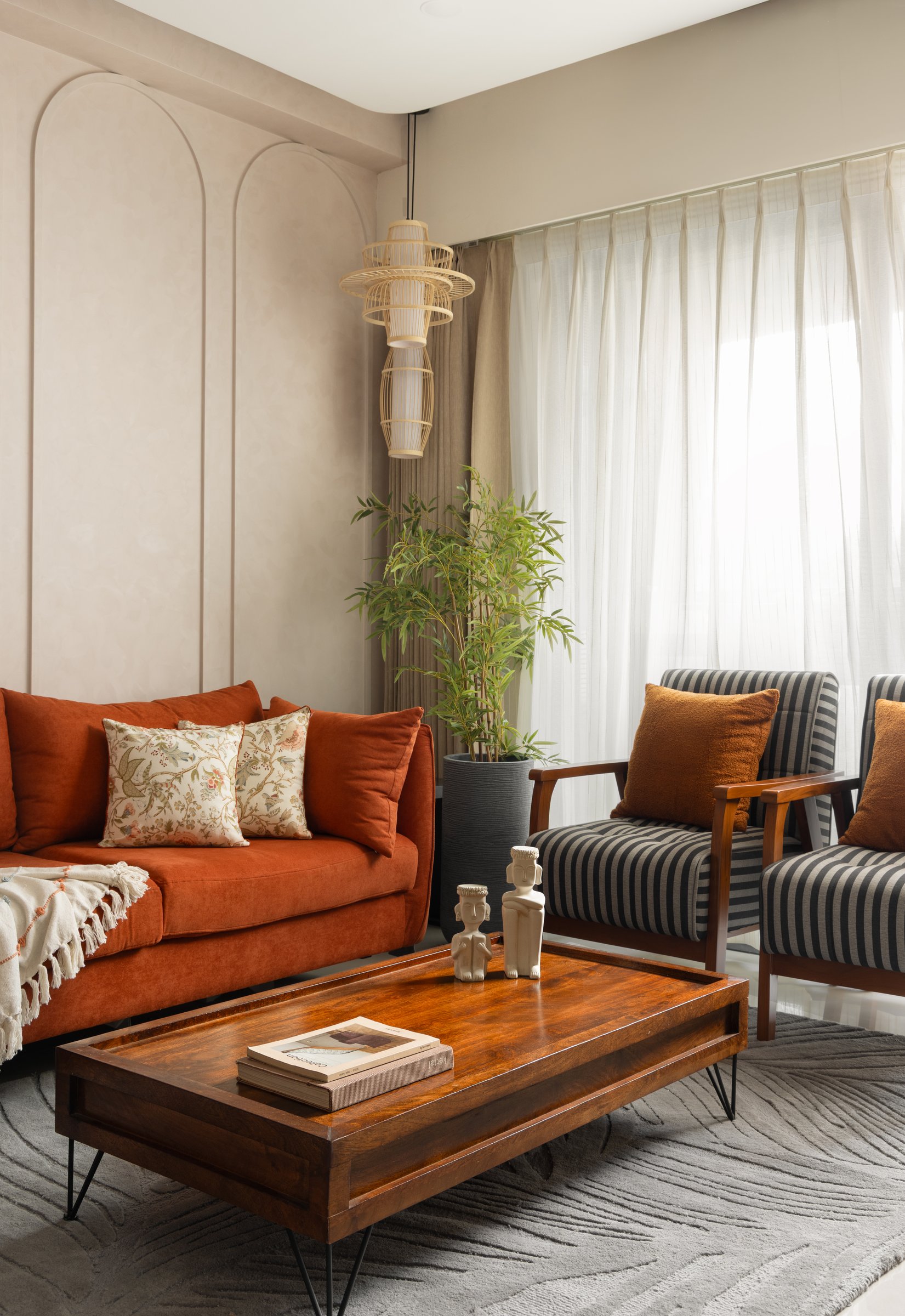 The seating arrangement read closer: rust upholstery, striped armchairs and a dark wood coffee table set the room's tactile register